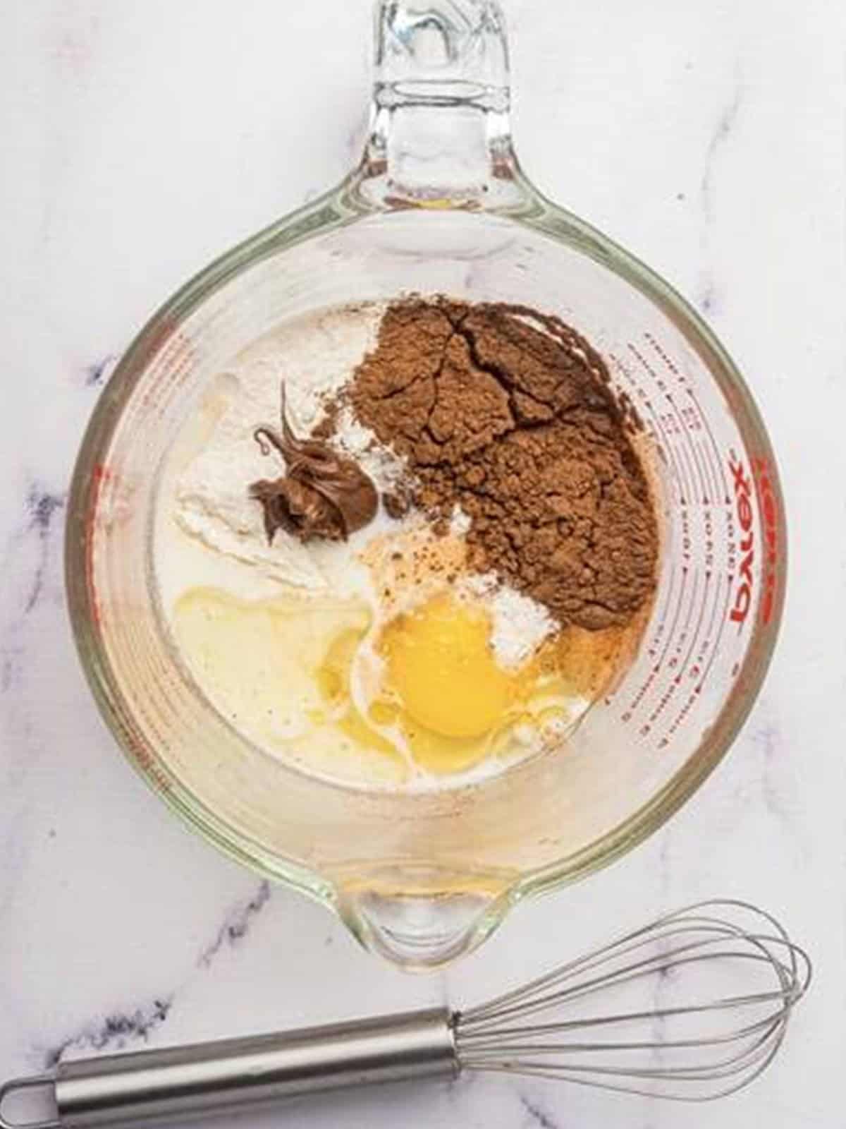 Mixing flour, cocoa, sugar, egg, milk, oil, and Nutella in a measuring bowl.