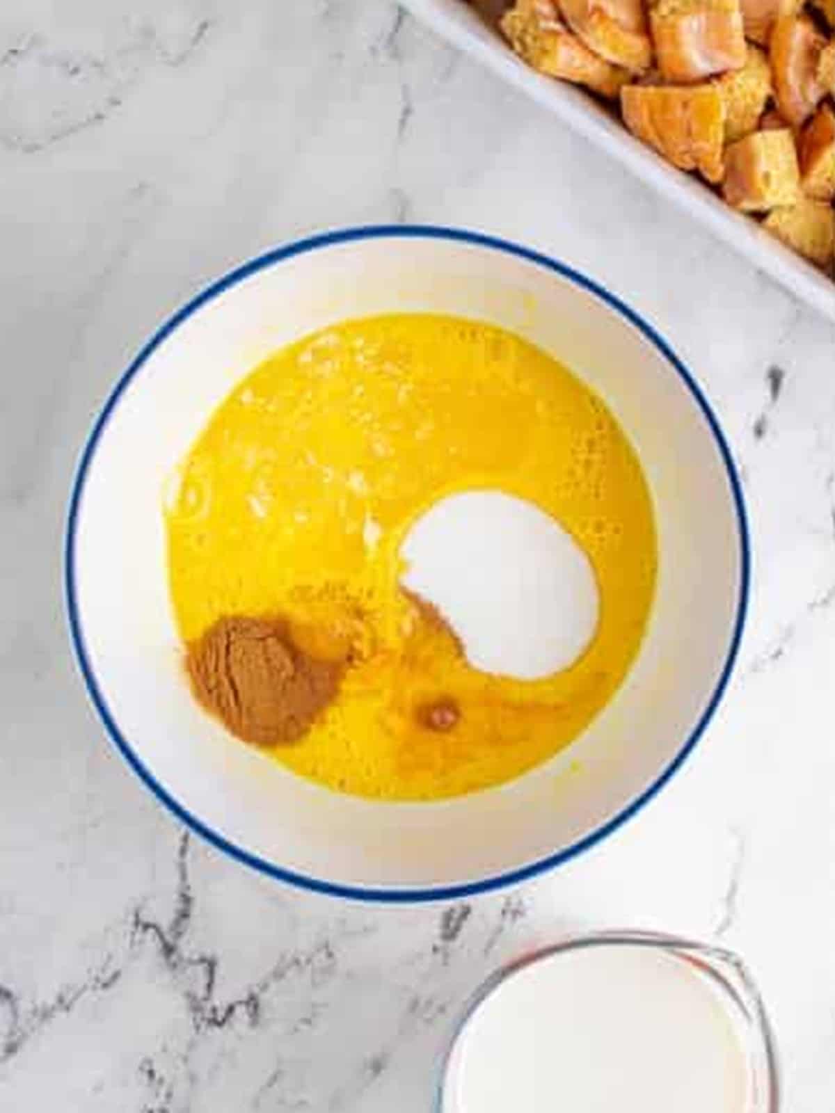 Eggs, sugar, cinnamon, and butter in a mixing bowl.