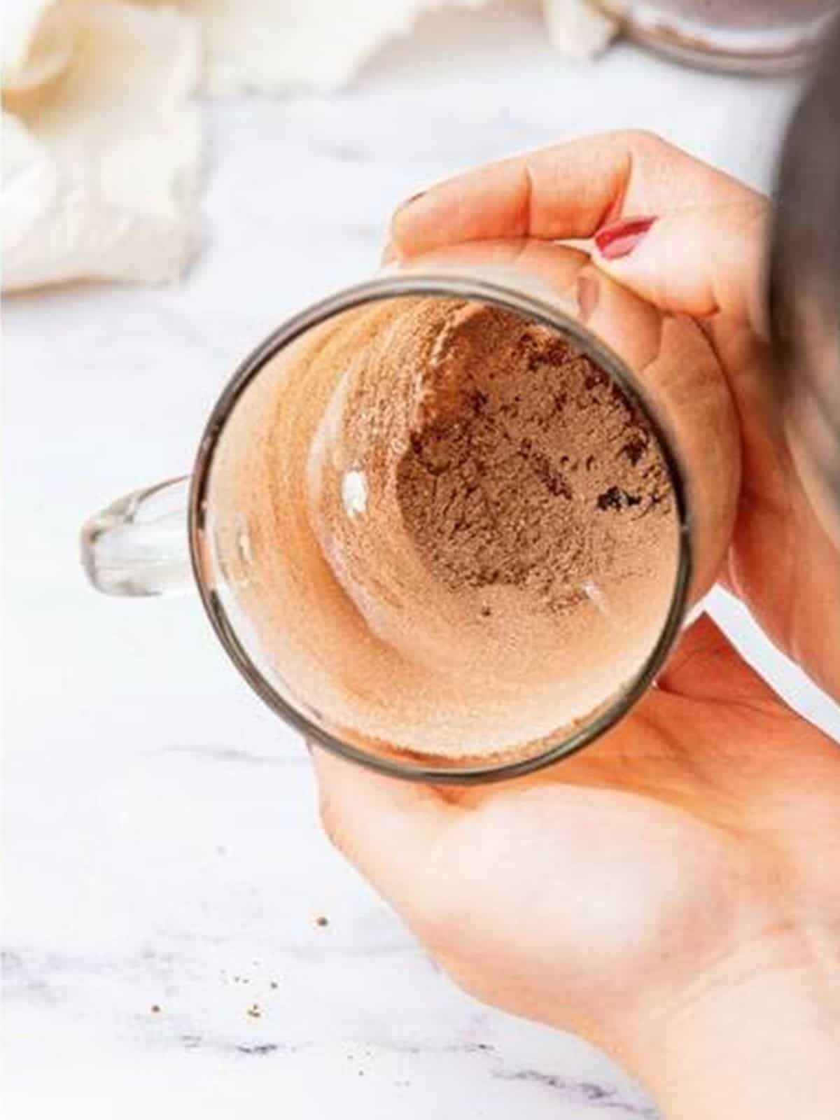Greasing a mug and dusting it with flour and cocoa.