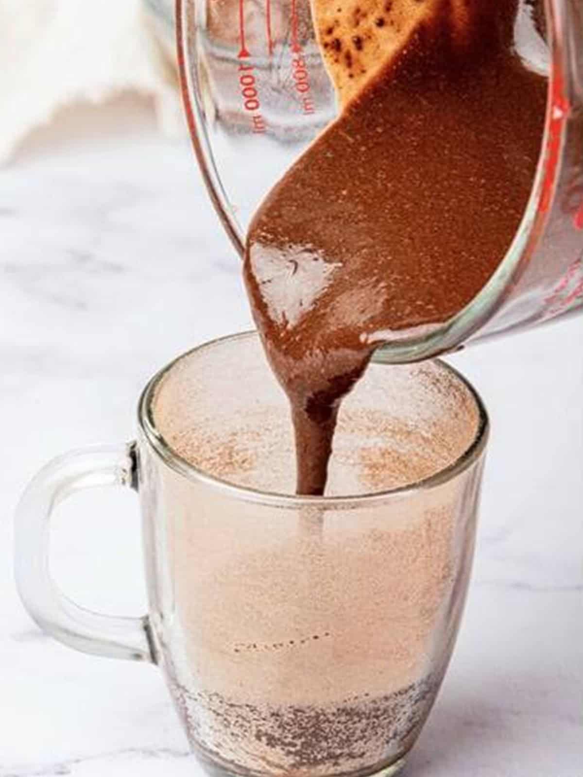 Pouring the chocolate batter into the prepared mug.