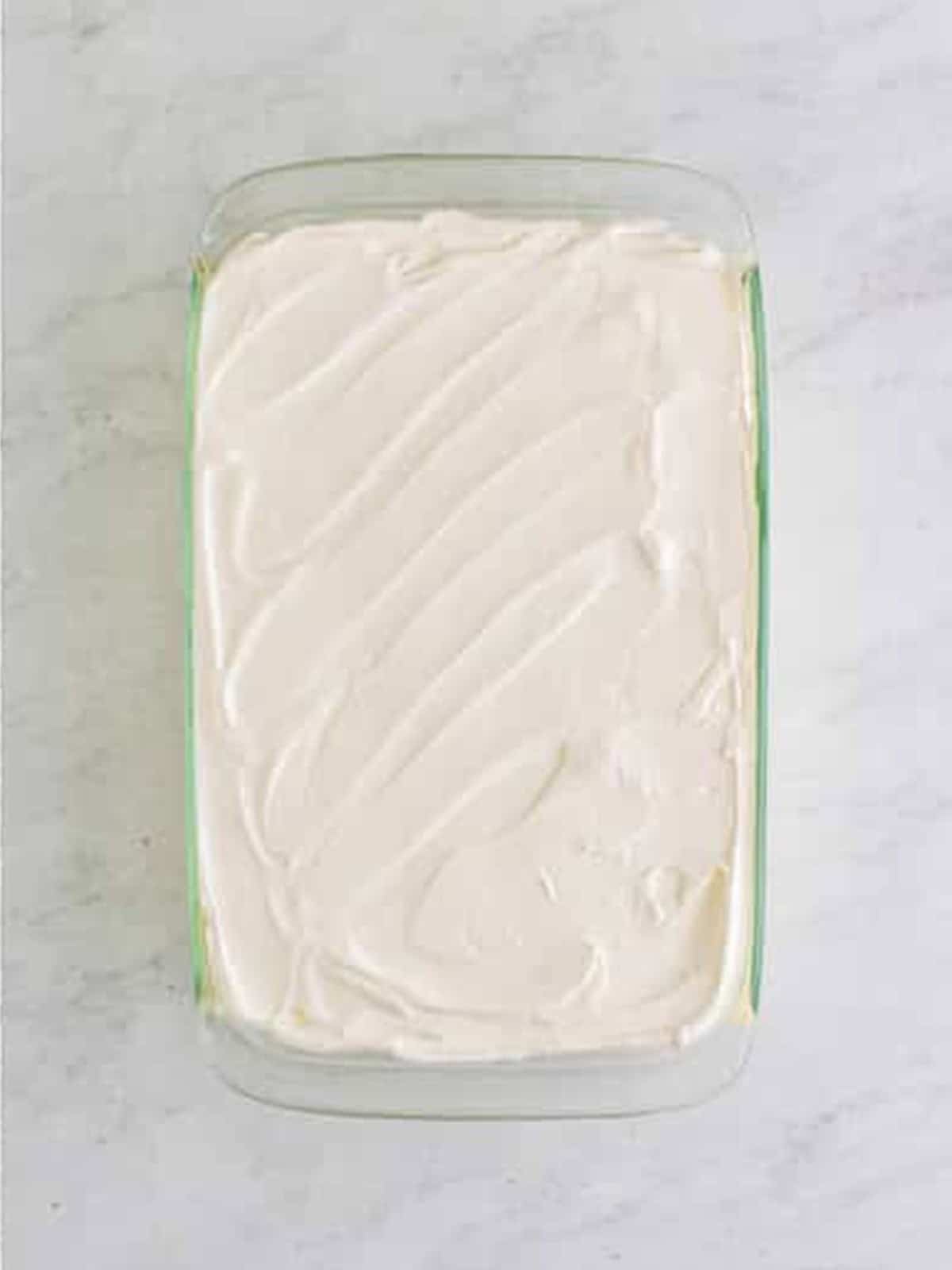Smoothing whipped topping over the top layer.