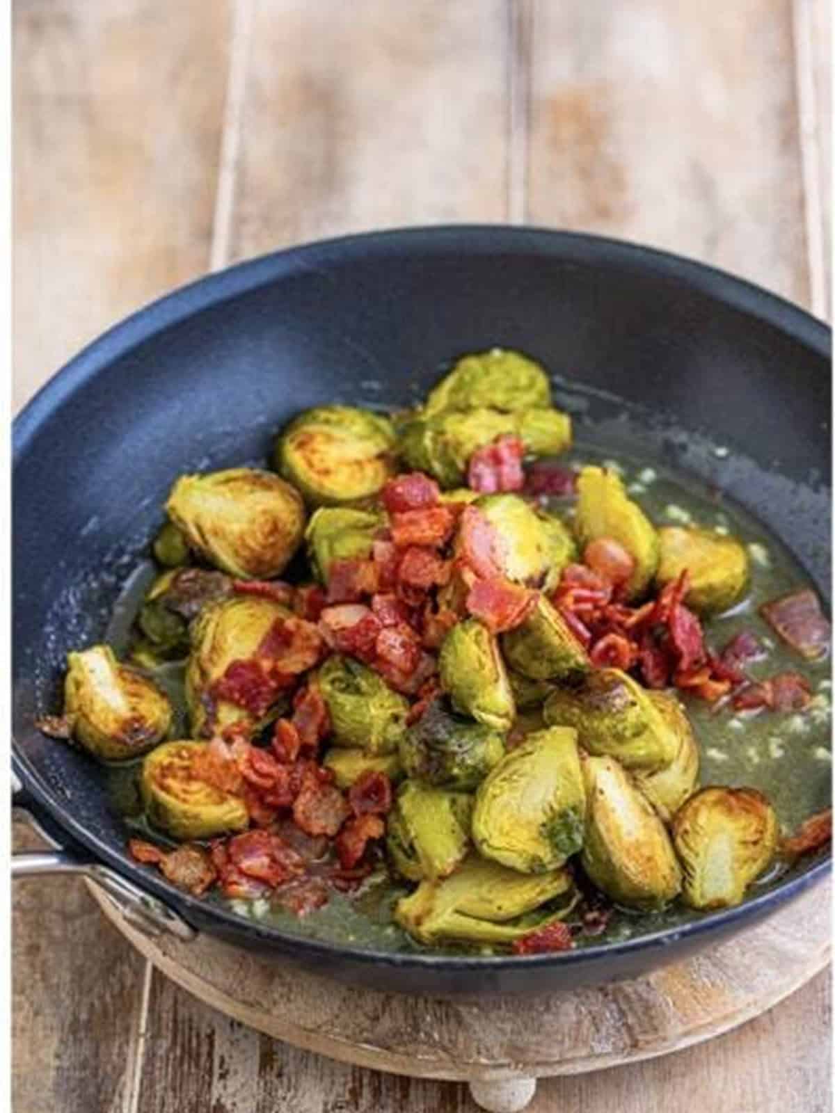 Roasted Brussels sprouts and bacon tossed in honey dijon glaze in a skillet.
