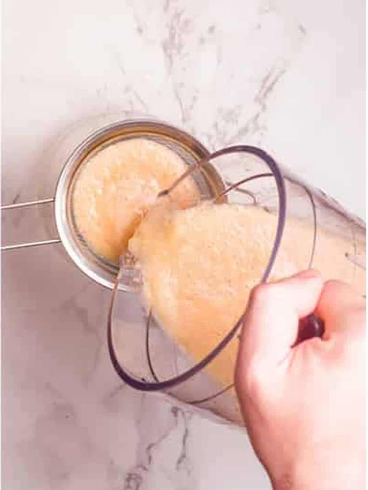Straining the blended Peach Arnold Palmer through a mesh strainer.