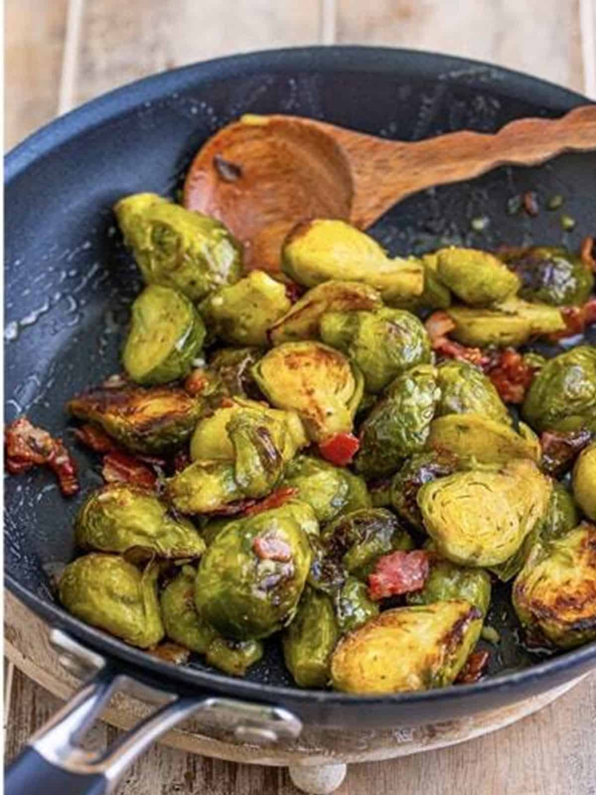 Finished glazed roasted Brussel Sprouts with Bacon in a skillet.