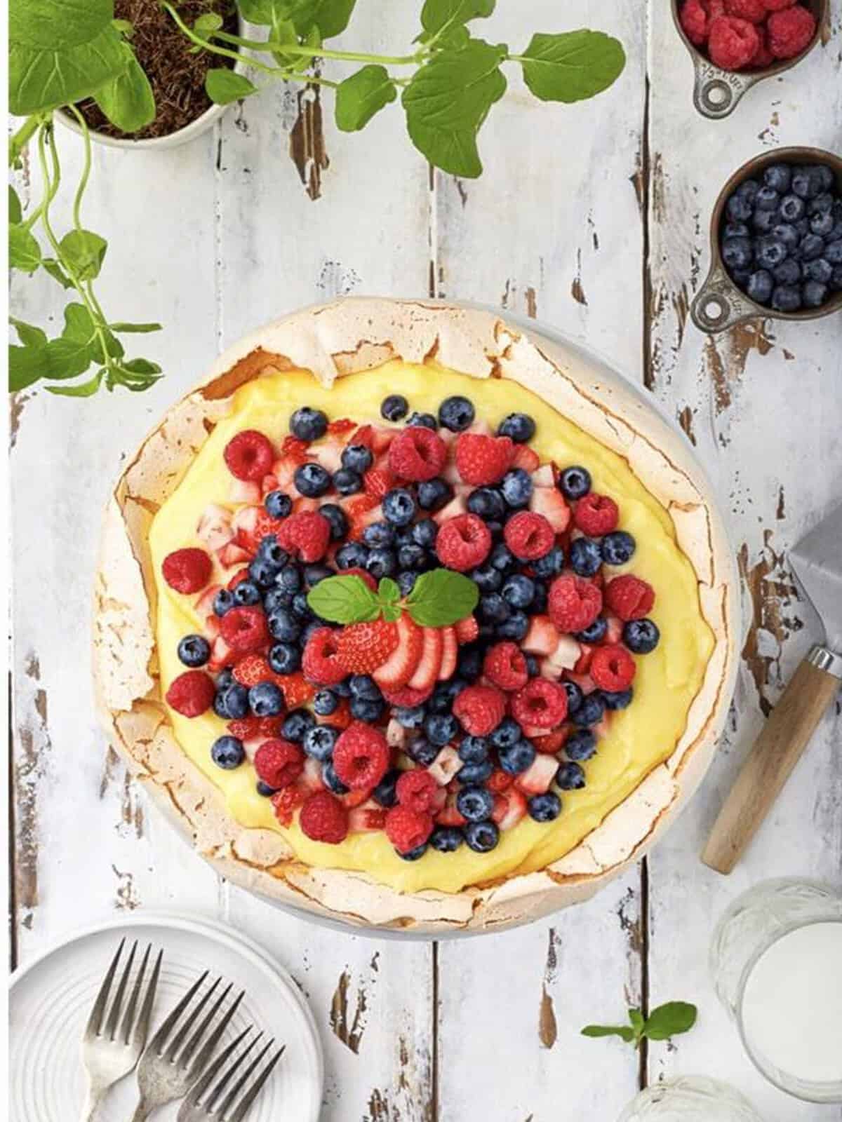 Finished Pavlova Recipe topped with fresh berries and whipped cream.