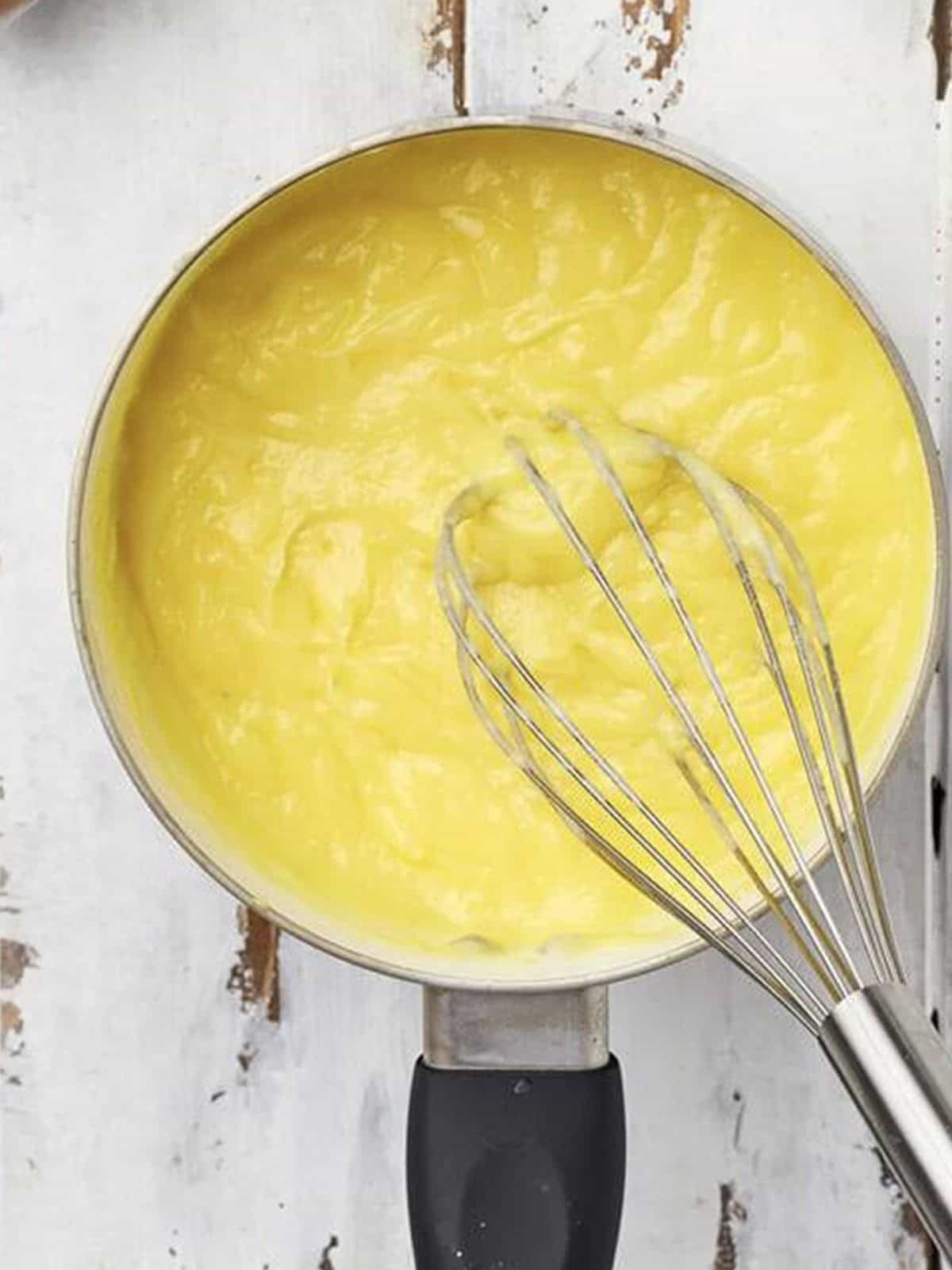 Cooked golden pastry cream whisked smooth in a saucepan.