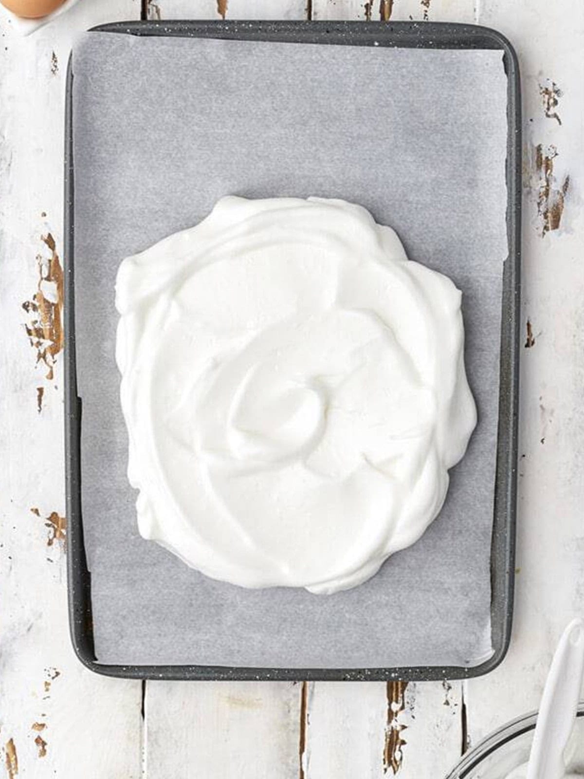 Meringue spread into a circle on a parchment lined baking tray.