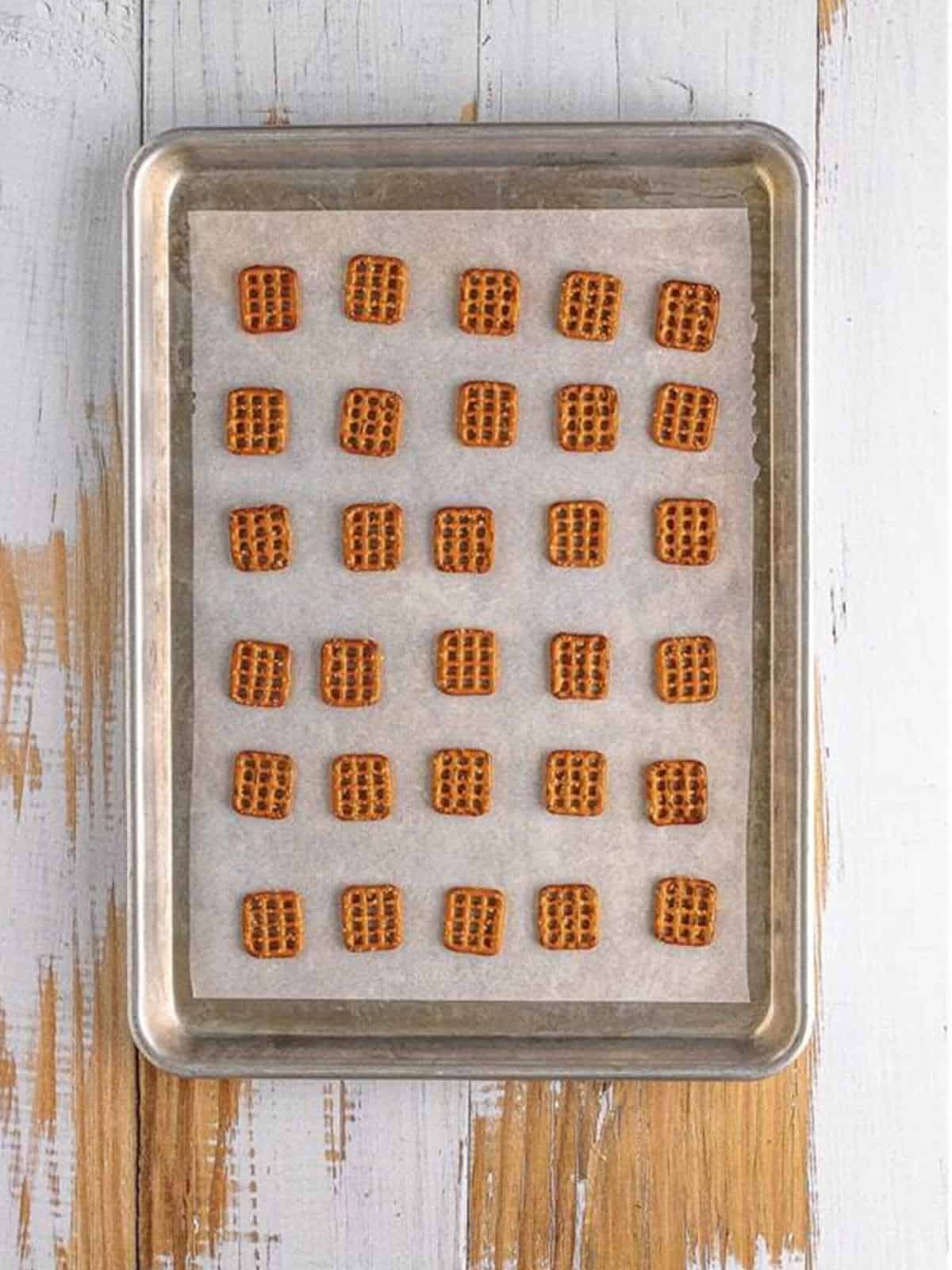 Square pretzels laid out on a parchment lined baking sheet.