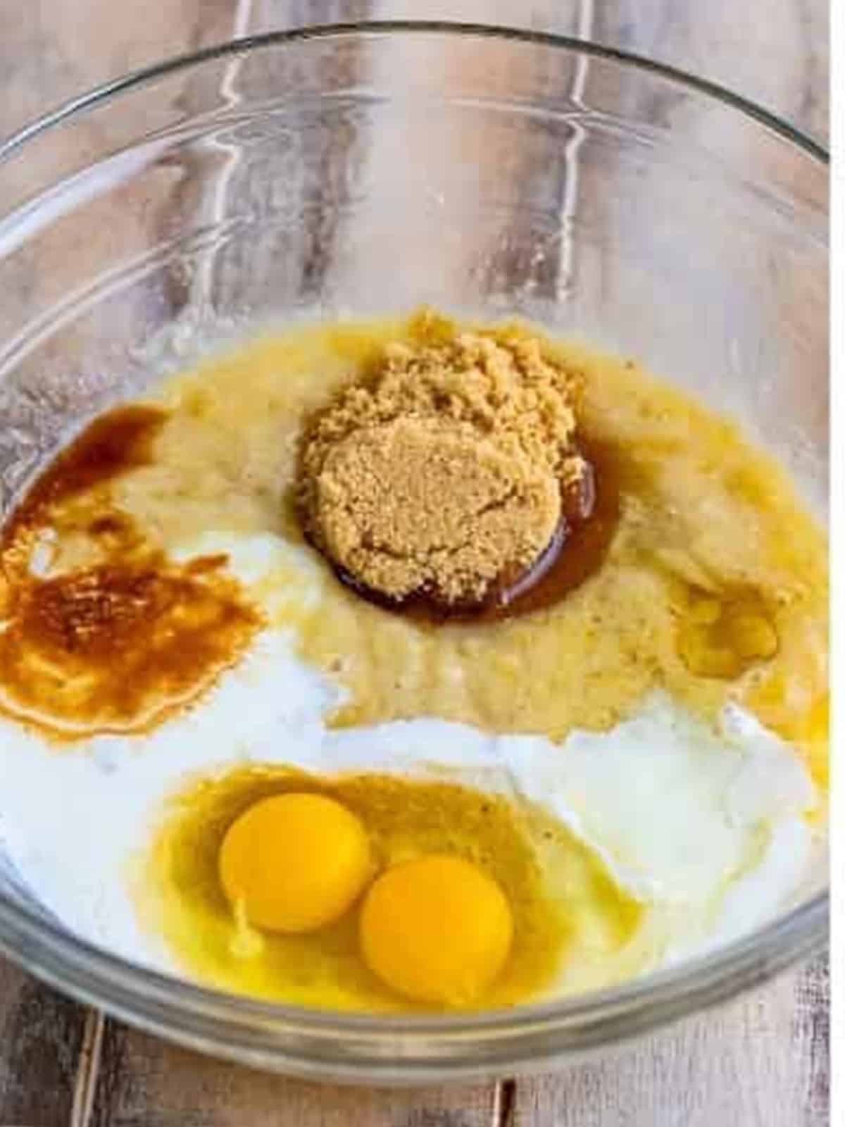 Mashed banana, brown sugar, eggs, buttermilk, and vanilla in a glass bowl.