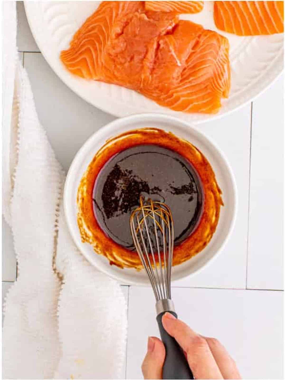 Whisking the hoisin glaze for air fryer salmon in a white bowl.