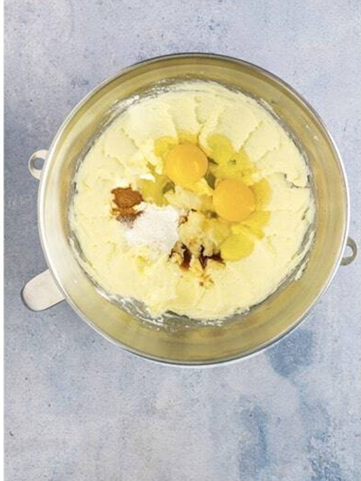 Adding eggs, vanilla, and cinnamon to the creamed butter.