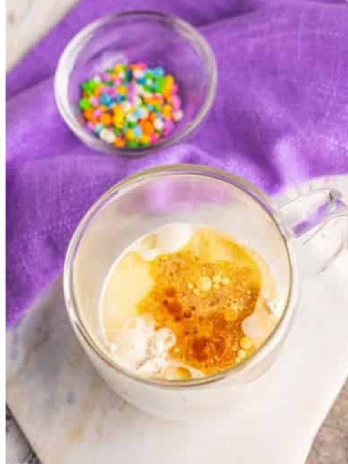 Adding milk, oil, and vanilla to the dry ingredients in the mug.