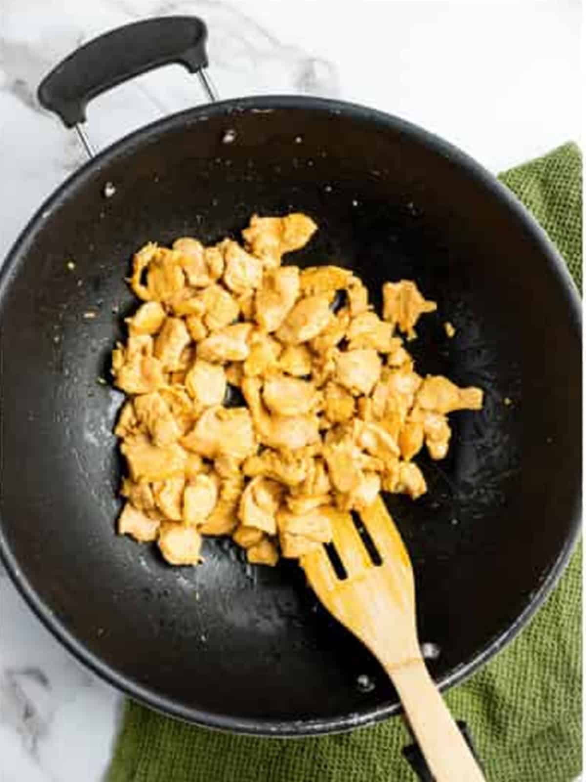 Cooking sliced chicken in a hot wok for drunken noodles.