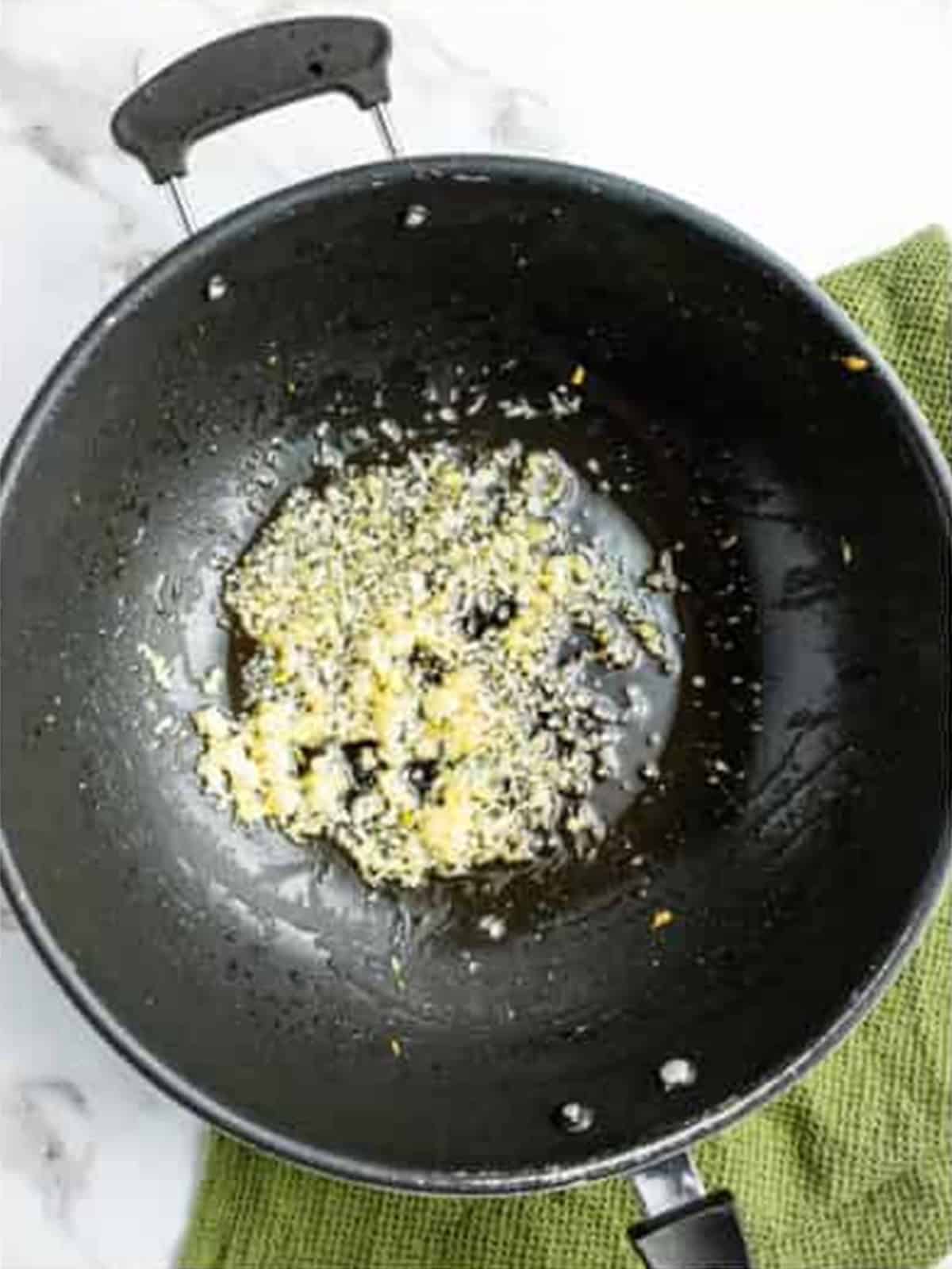 Sauteing garlic, ginger, and shallots in a wok.