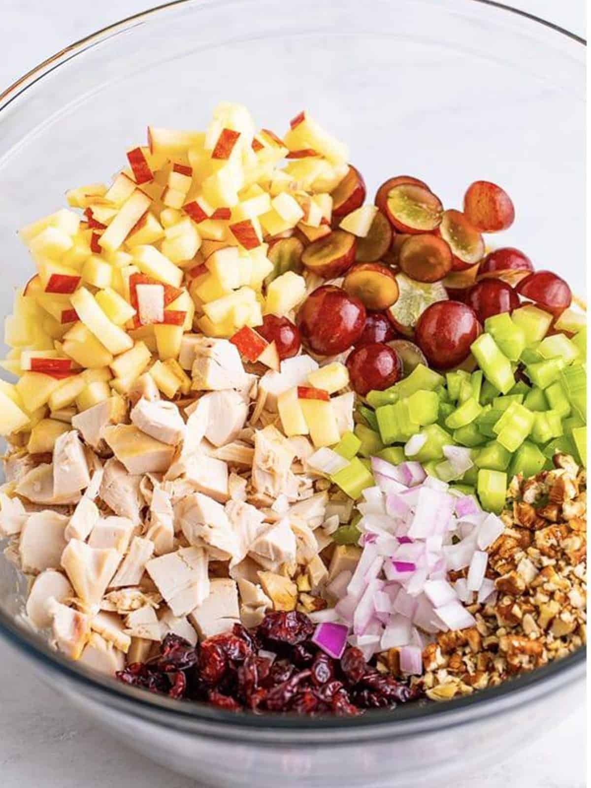 Adding diced chicken, grapes, apple, cranberries, and pecans to the dressing for chicken salad.