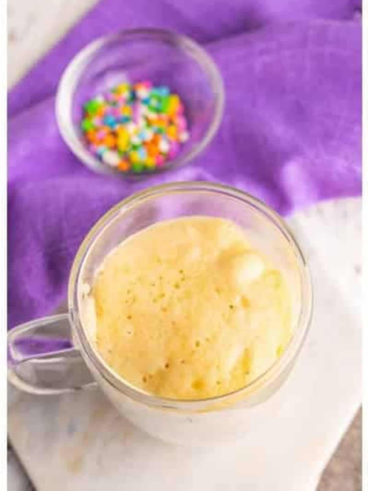 The cooked vanilla mug cake risen in the mug after microwaving.