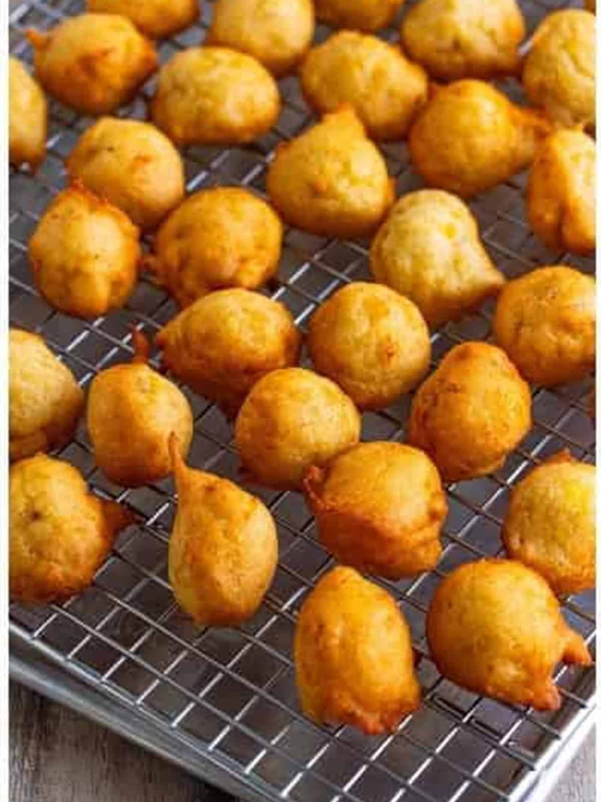 Golden fried banana fritters draining on a wire rack.