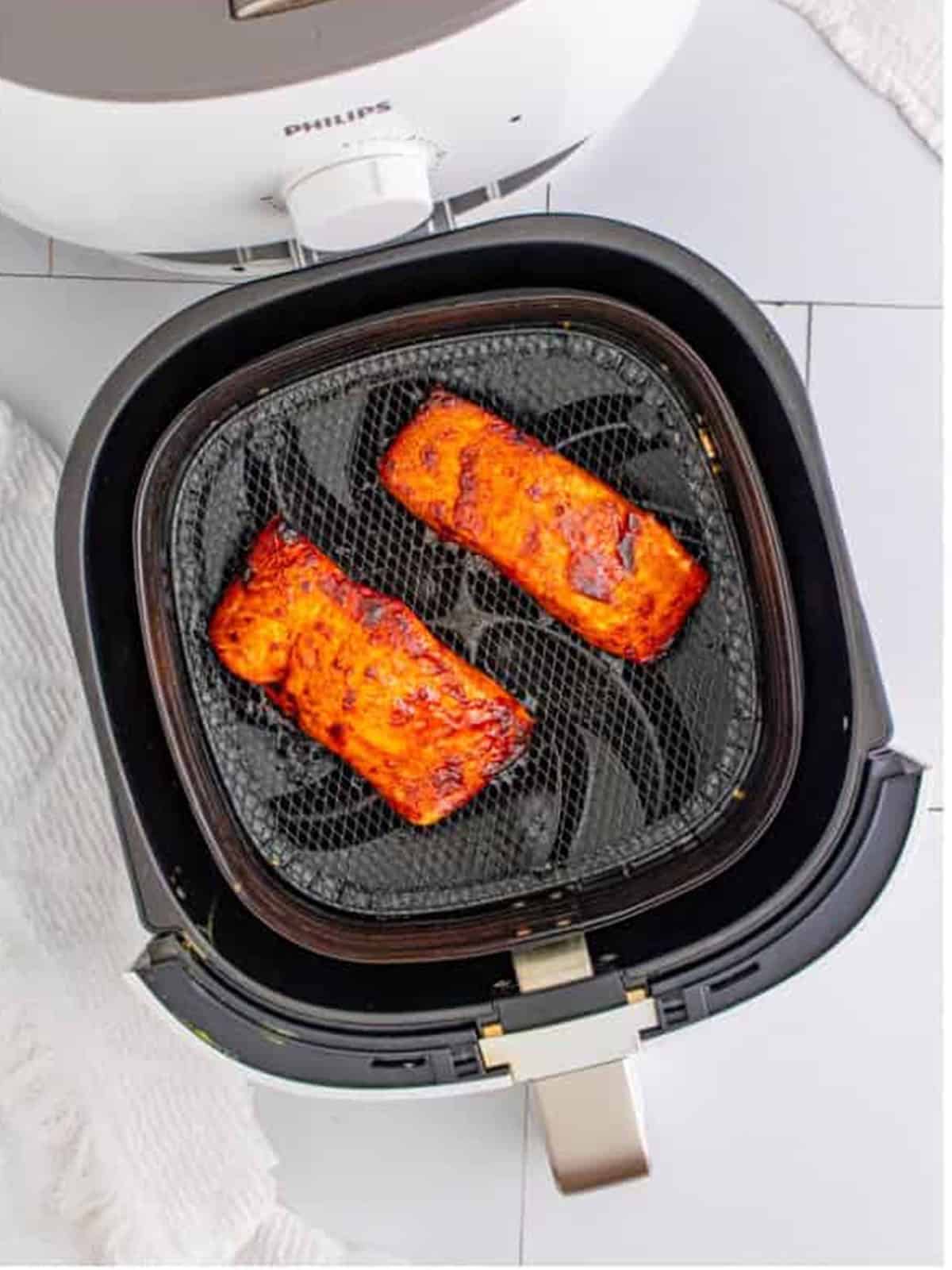 Finished glazed air fryer salmon in the basket ready to serve.