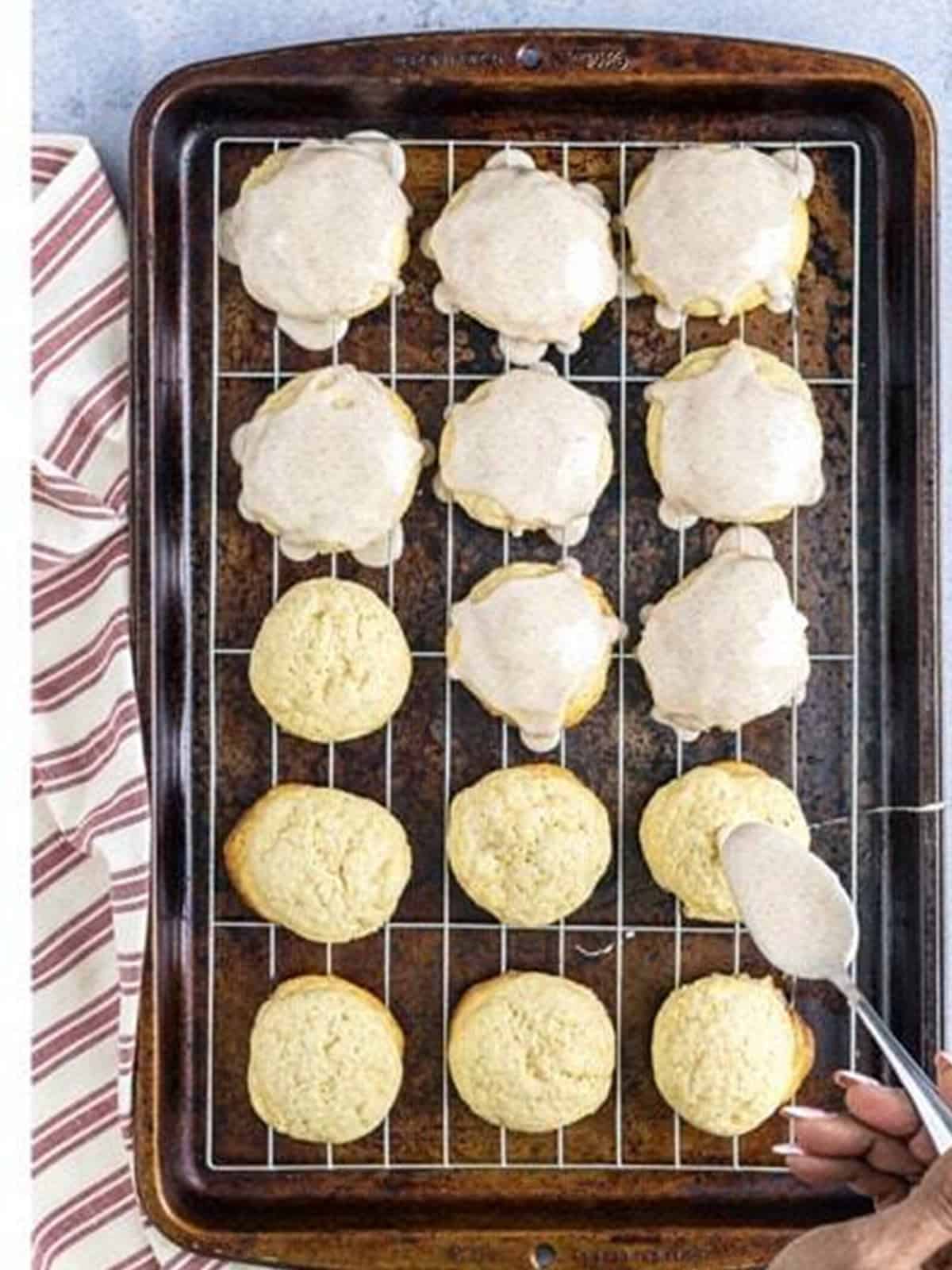Glazing the cooled cinnamon tea cakes on a wire rack.