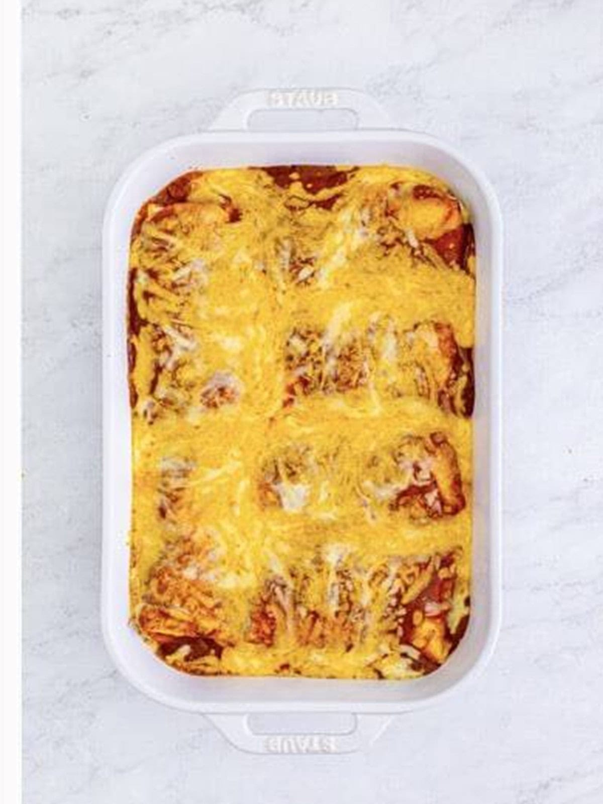 Baked smothered burritos bubbly and golden in a white baking dish.