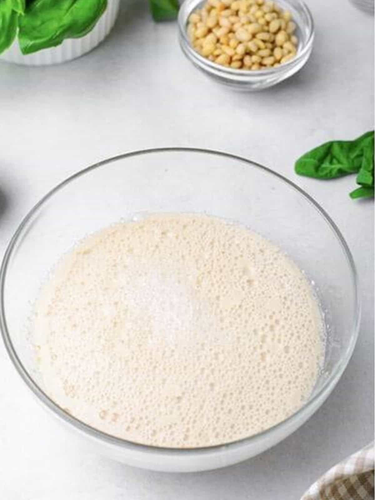 Yeast blooming in warm water and sugar in a glass bowl for challah bread dough.