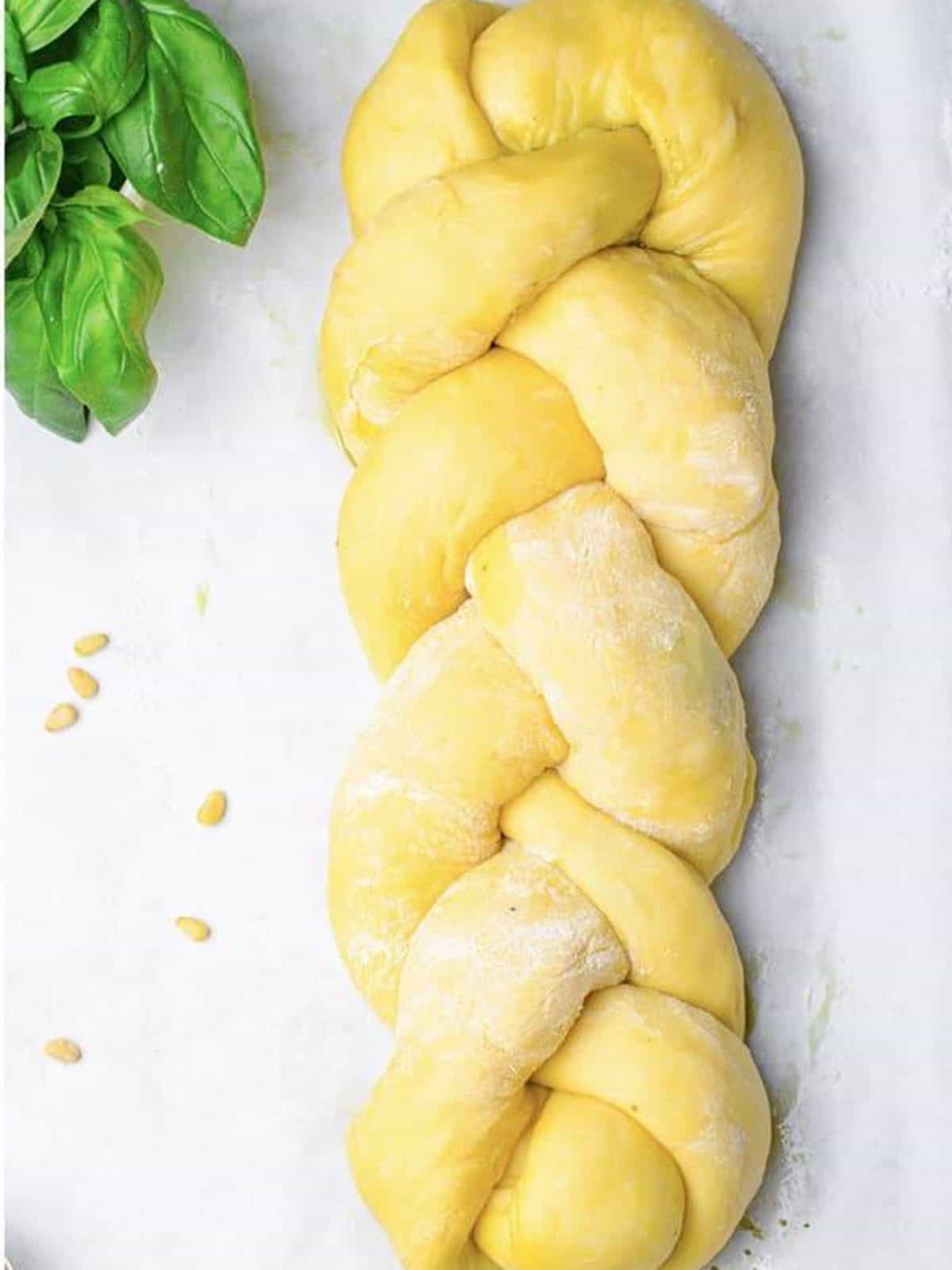 Three pesto stuffed dough ropes braided into a challah bread loaf.