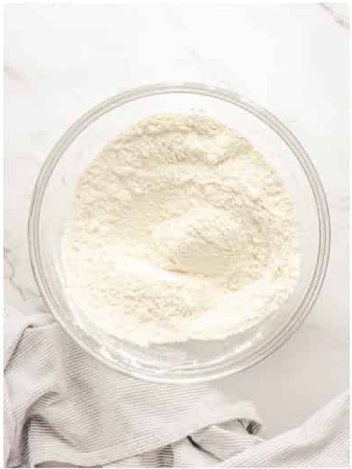 Flour, sugar, baking powder, and salt whisked together in a glass bowl.