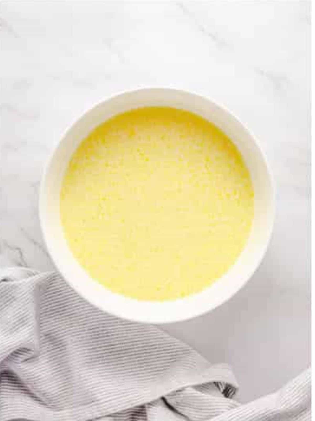 Egg, milk, and melted butter whisked together in a white bowl.