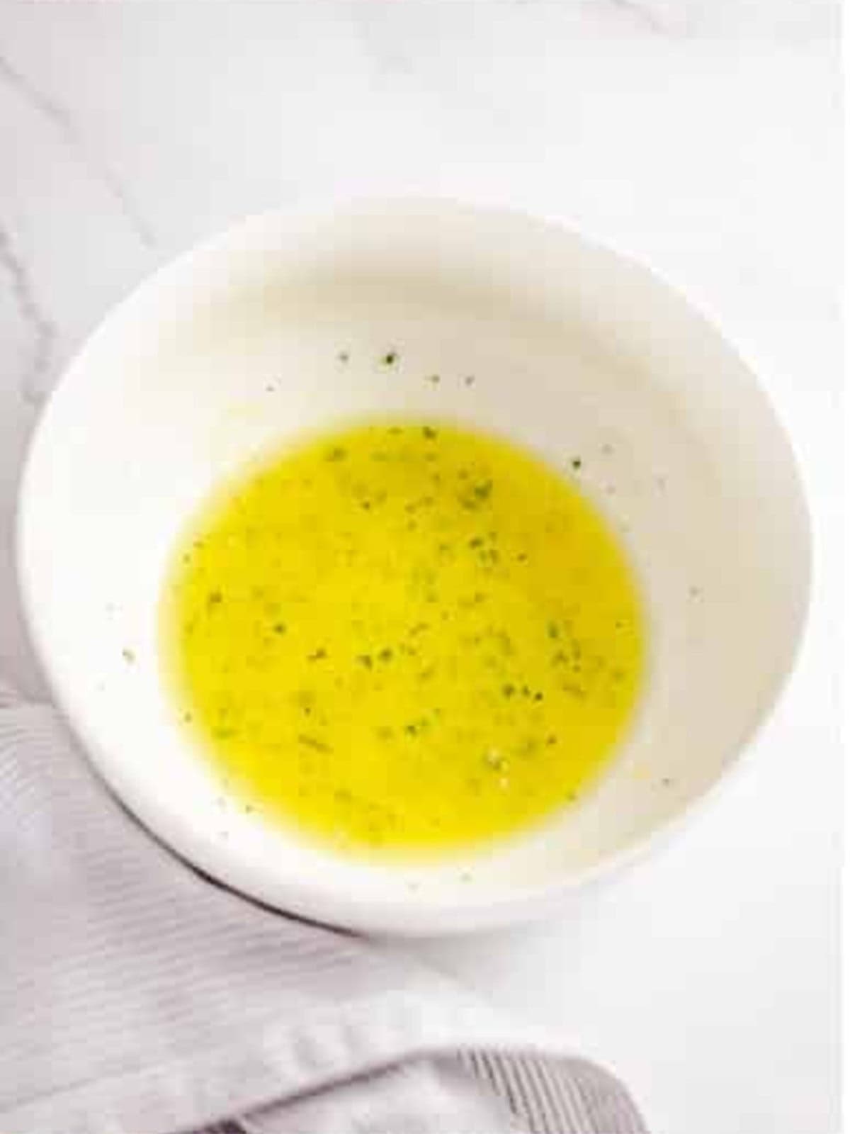 Garlic butter topping mixed with parsley in a white bowl.