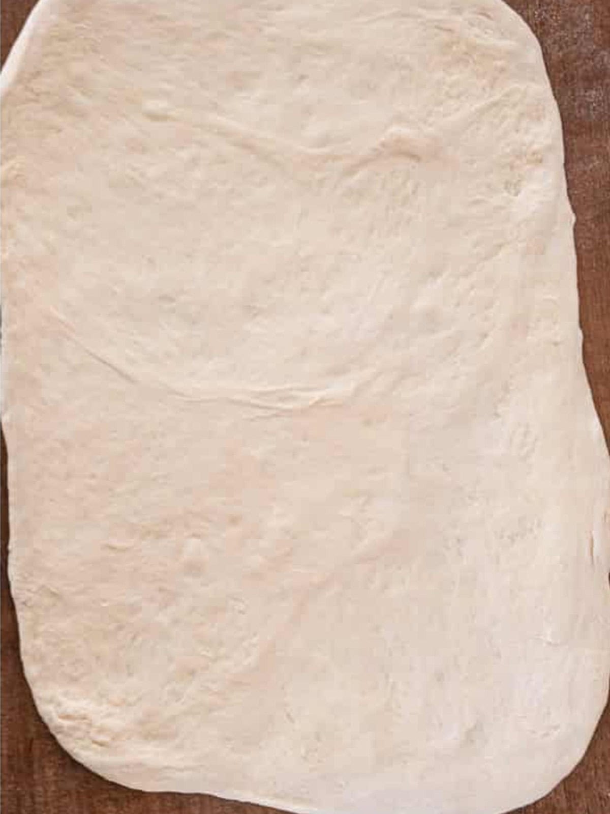 Pizza dough rolled out into a flat rectangle for cheese stuffed breadsticks.