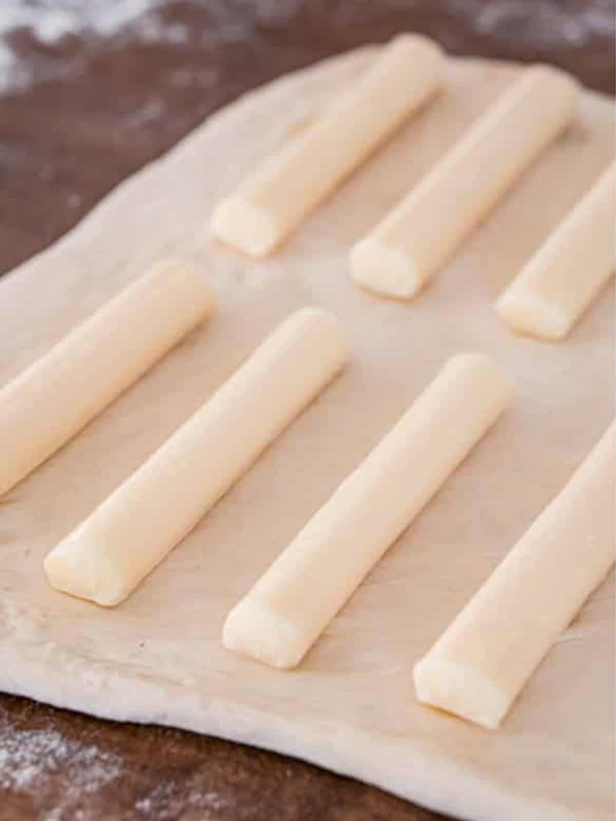 String cheese arranged in rows on rolled pizza dough for cheese stuffed breadsticks.