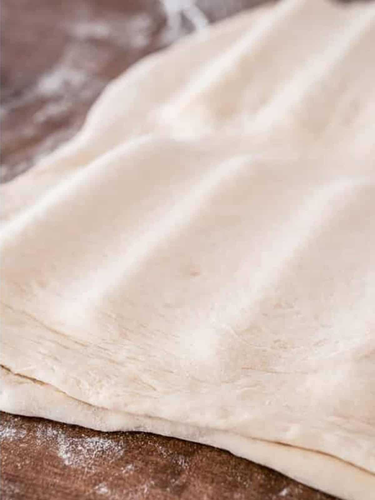 Second sheet of pizza dough laid on top and pressed around the string cheese.