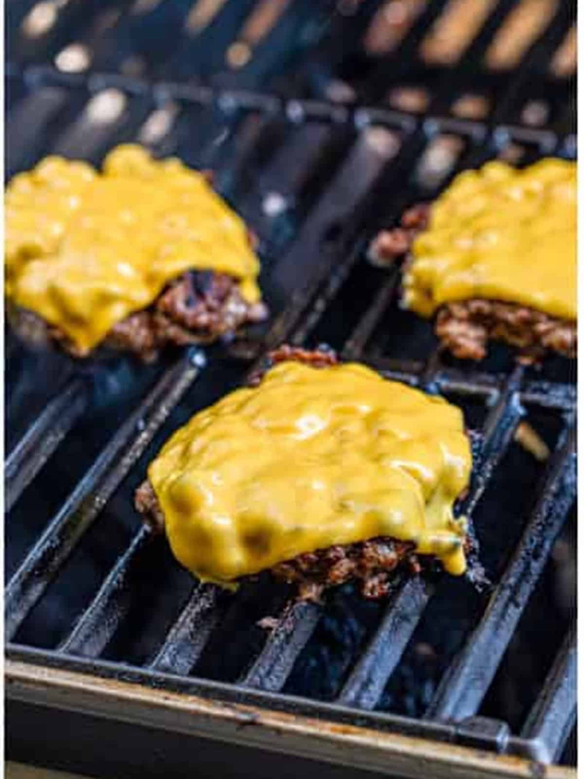 American cheese melting on top of grilled cheeseburger patties.