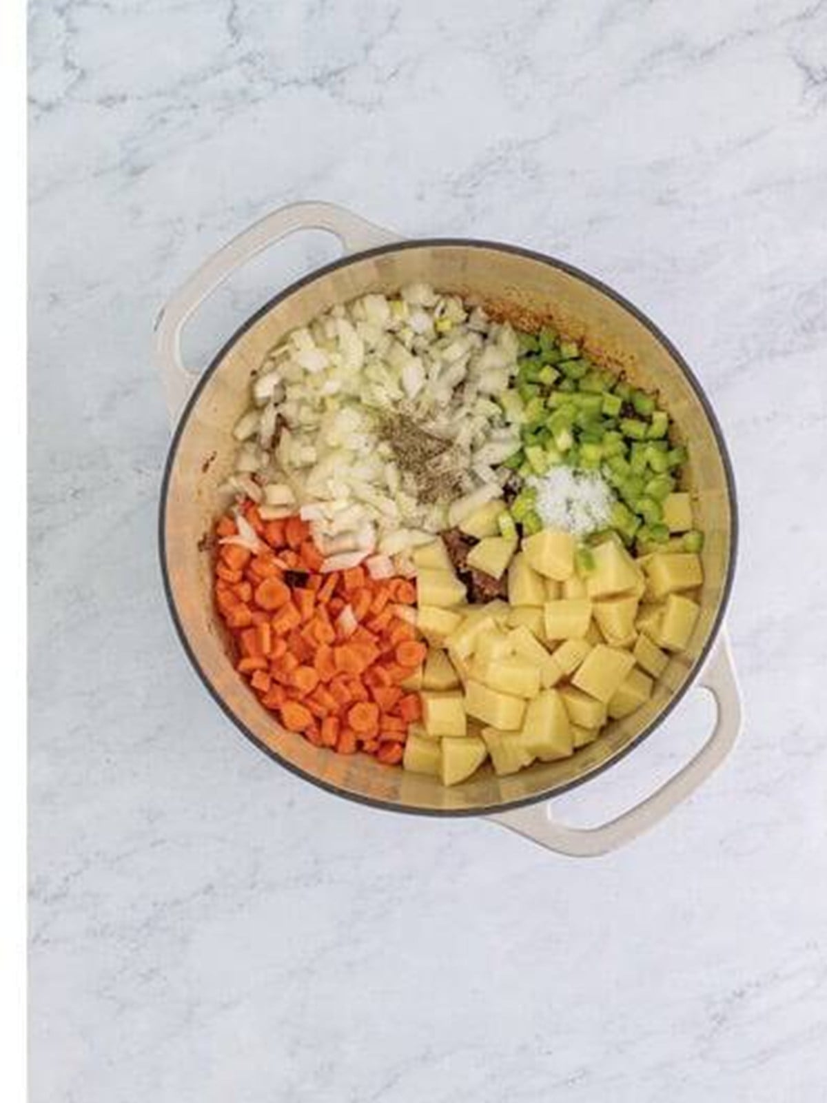 Diced potatoes, onion, carrot, and celery added to the browned ground beef in the pot.