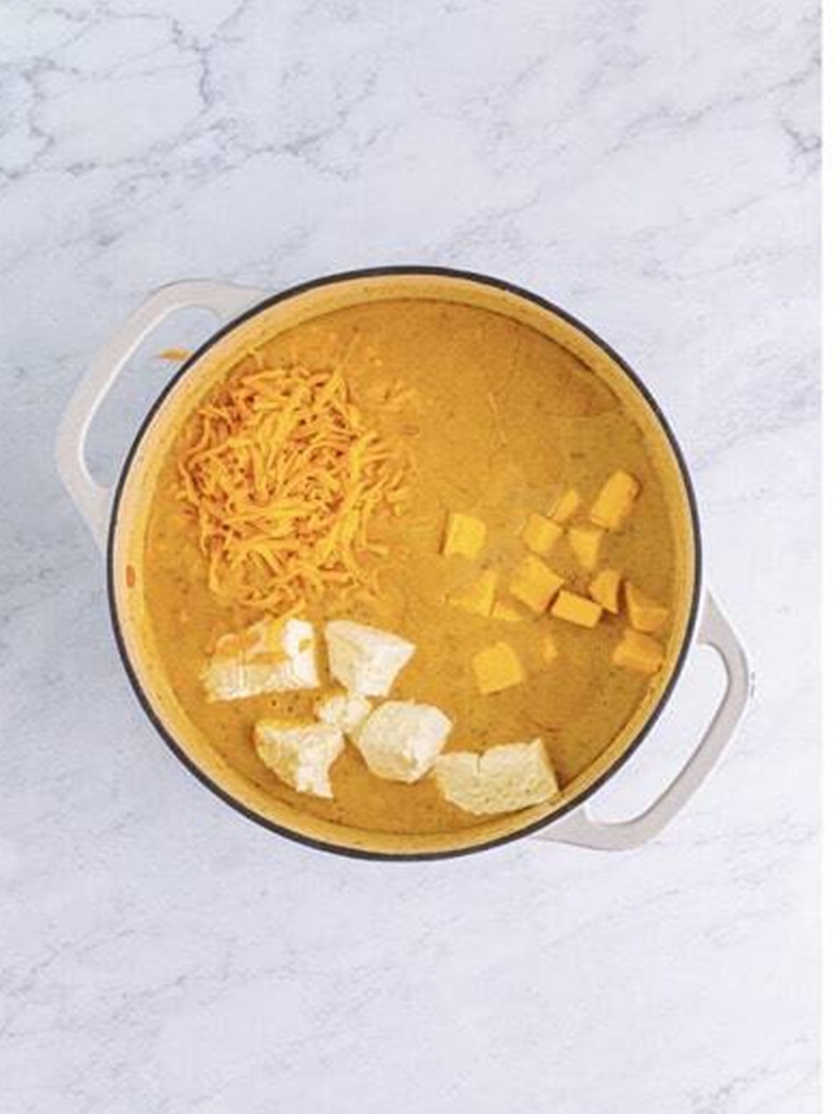 Cream cheese, Velveeta, and cheddar added to the soup to melt into a creamy cheeseburger soup.