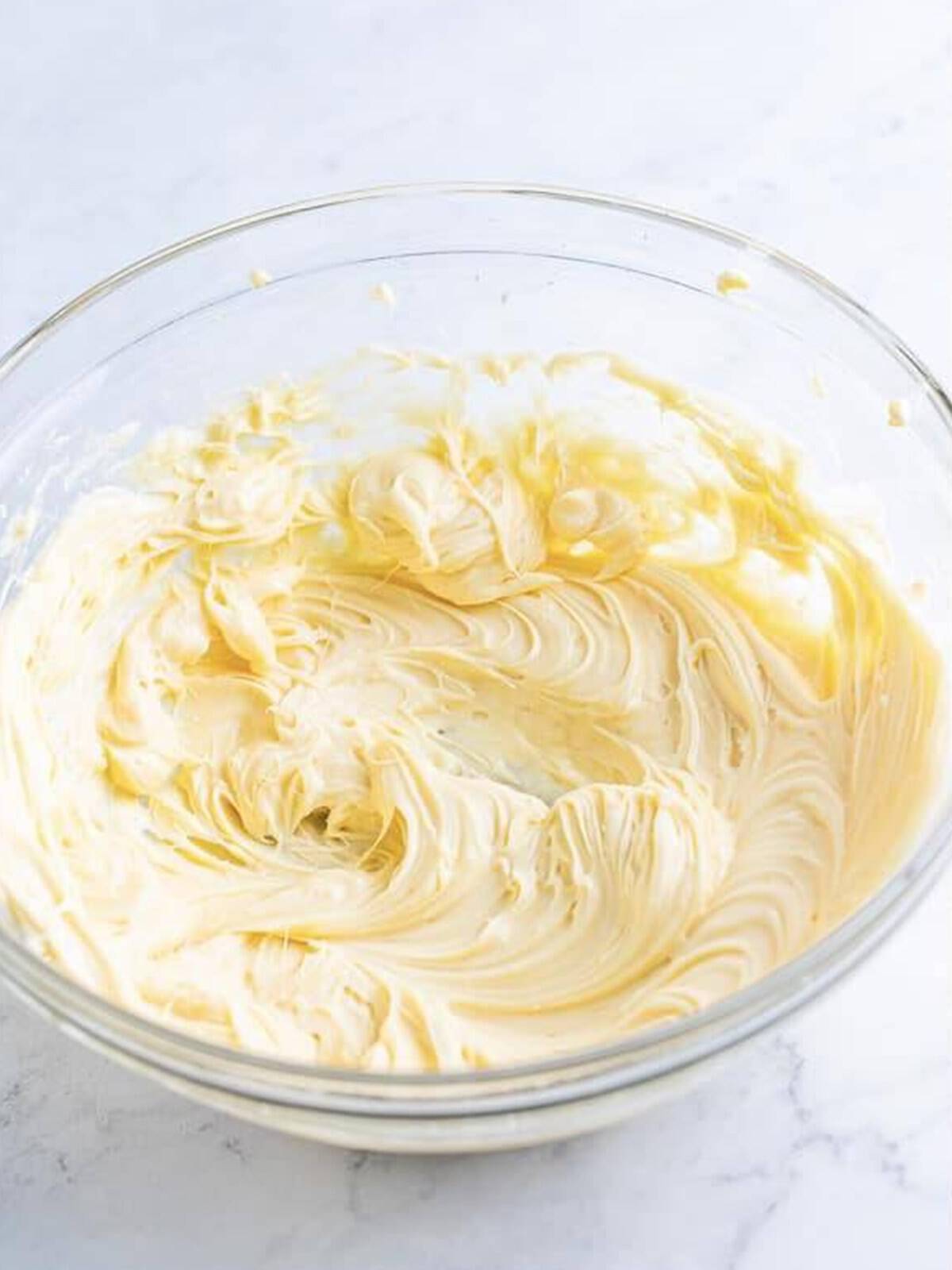 Cream cheese, powdered sugar, and vanilla whipped smooth in a glass bowl for cheesecake dip.