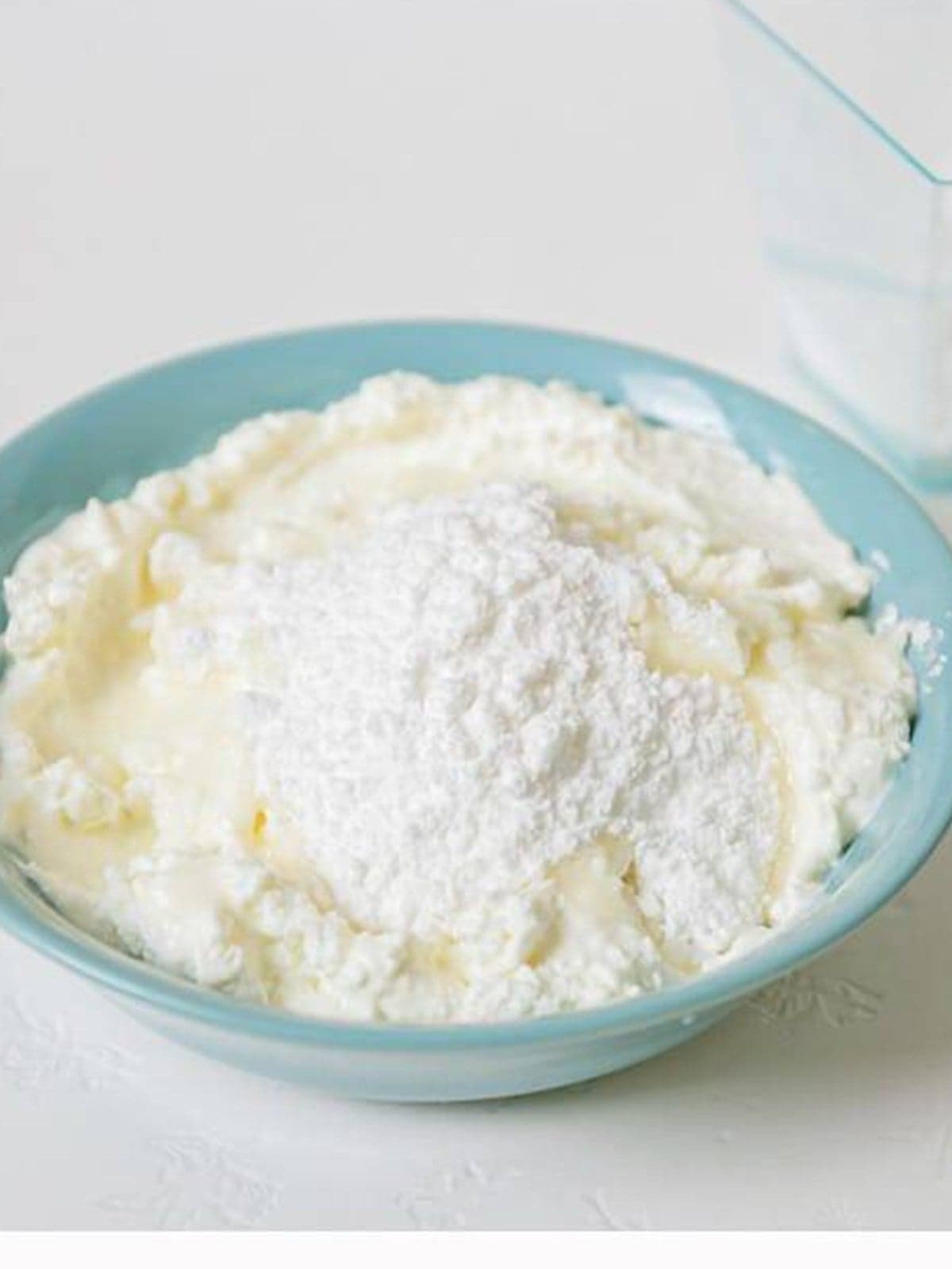 Cream cheese and powdered sugar in a bowl before mixing the cheesecake filling.