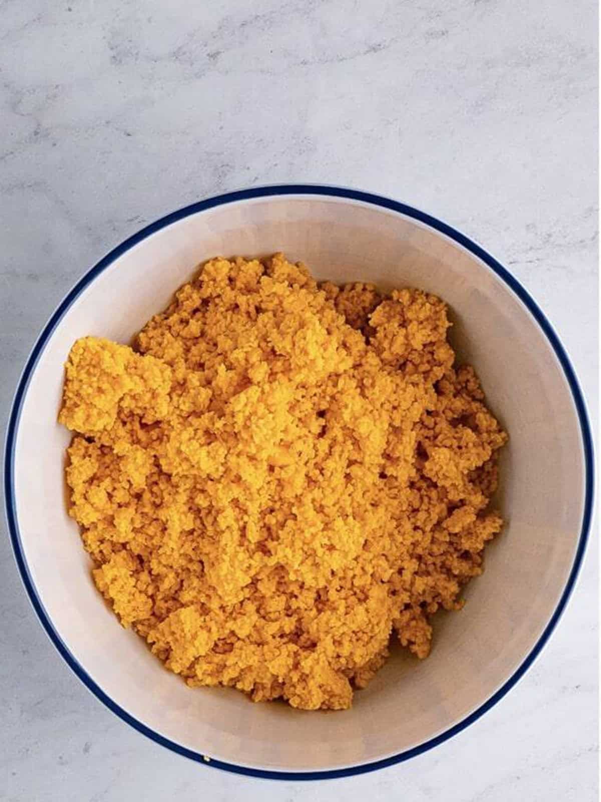Cheez-It cracker dough pulsed into moist crumbs in a bowl.