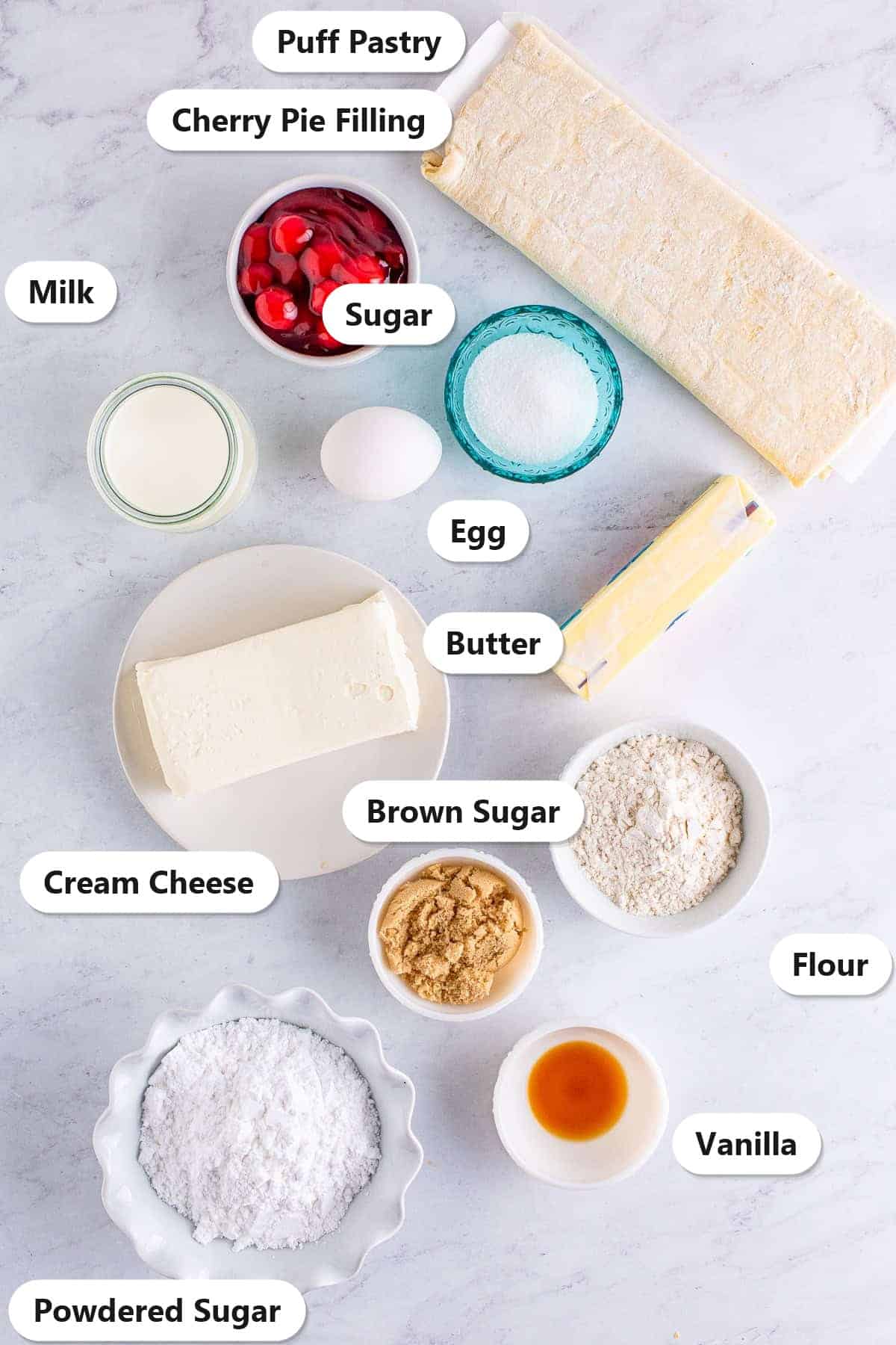 Ingredients to make a Cherry Danish laid out and labeled on a marble counter.