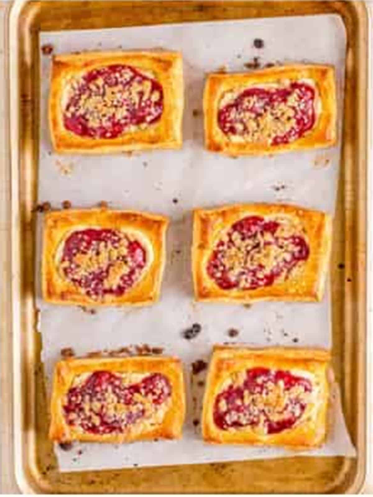 Golden baked Cherry Danishes on a parchment lined sheet tray.