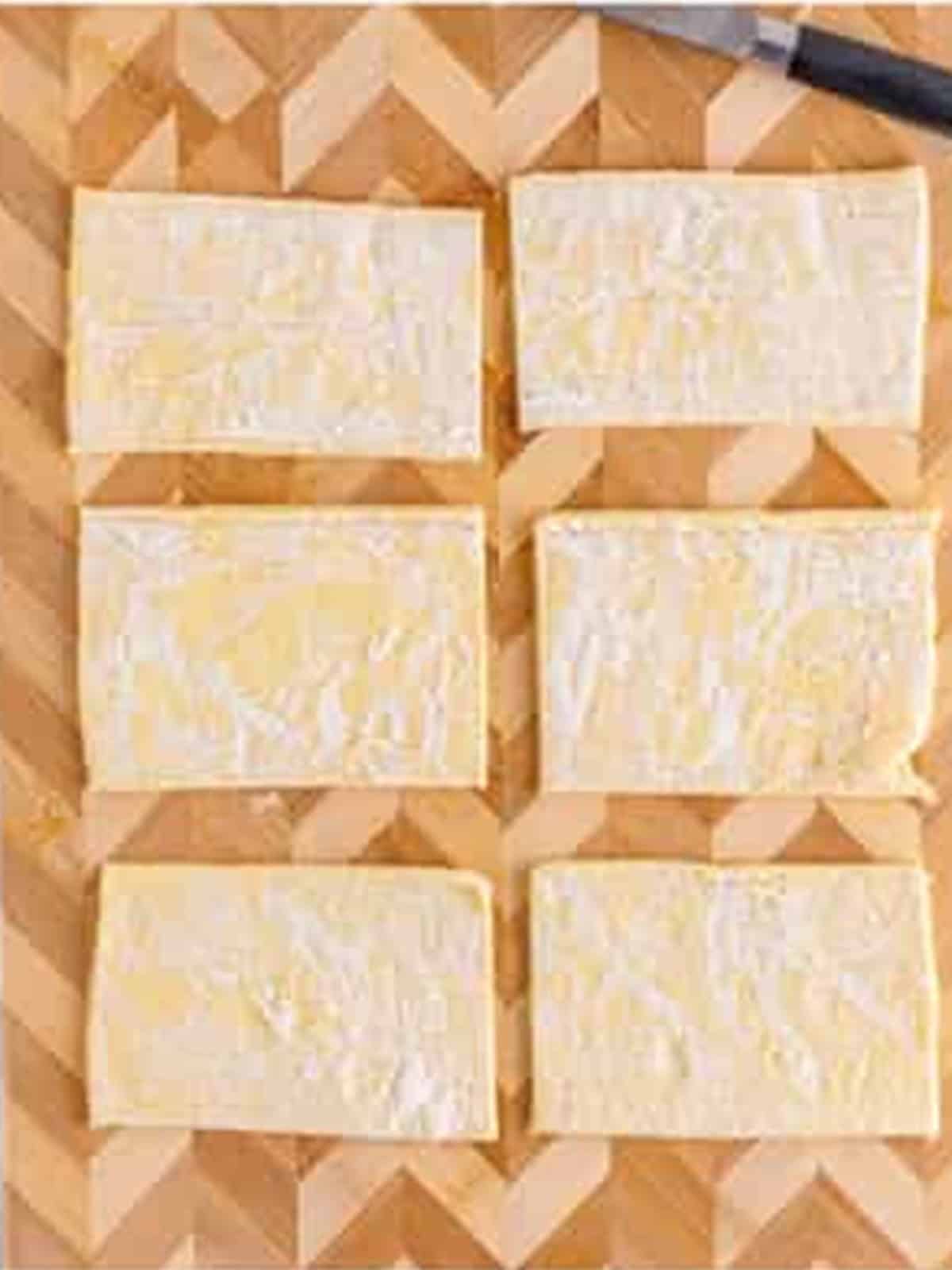 Puff pastry sheet cut into six rectangles on a cutting board for Cherry Danish.