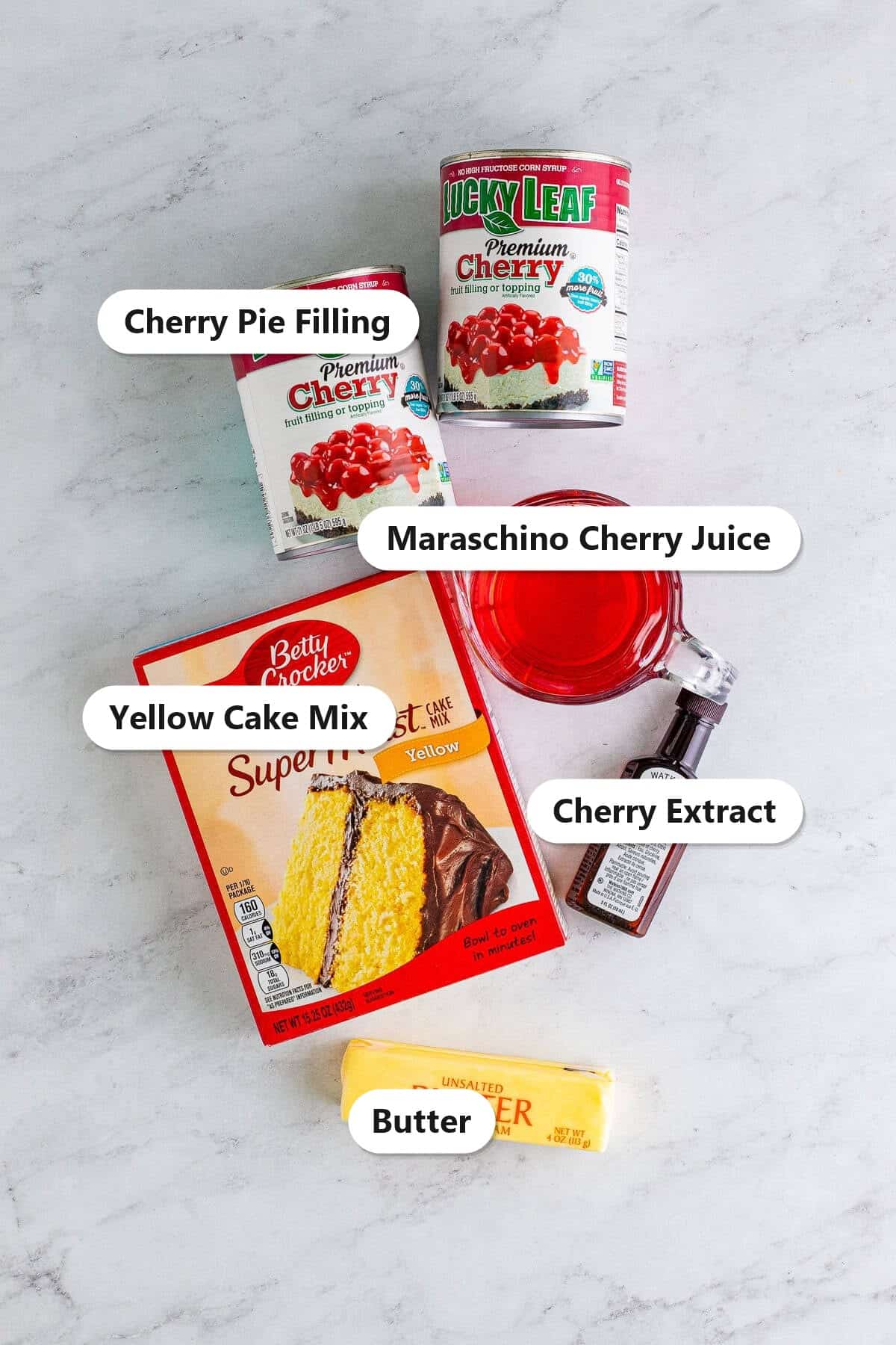 Labeled ingredients to make cherry dump cake including cherry pie filling, yellow cake mix, butter, and cherry extract.
