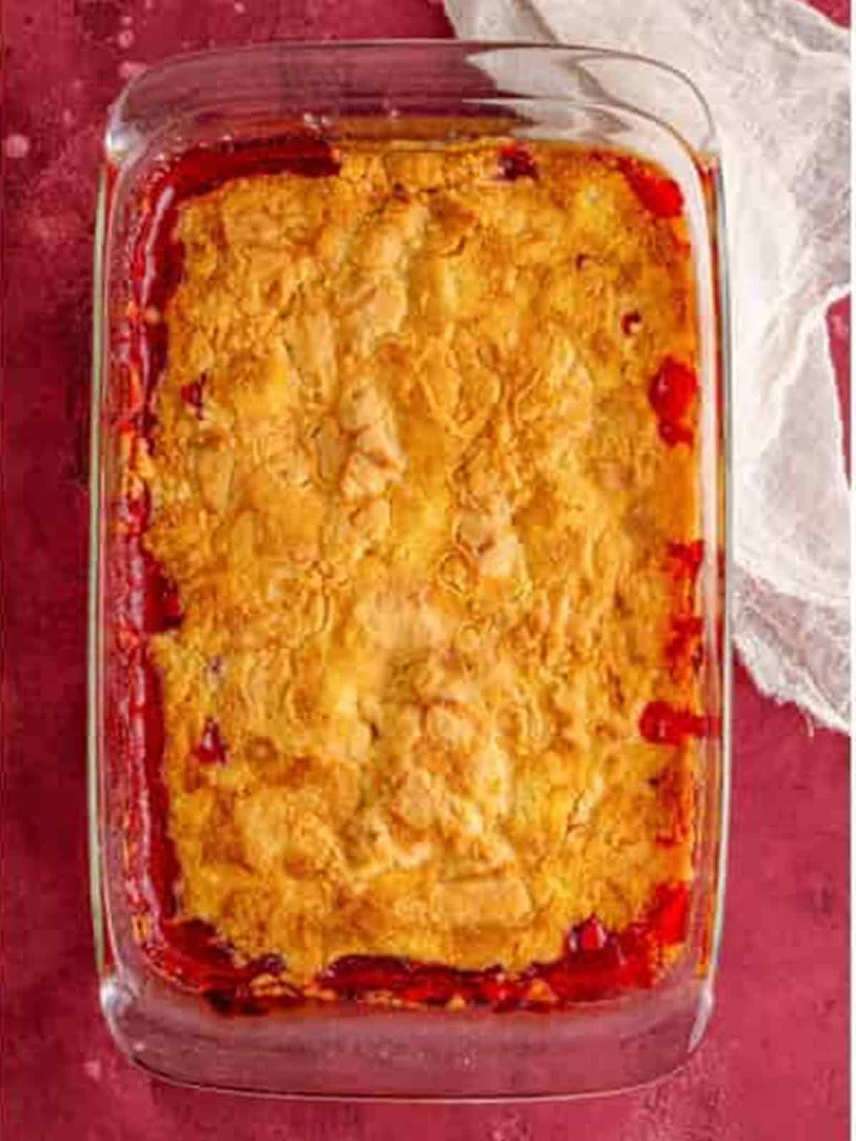 Baked golden and bubbly cherry dump cake in a glass baking dish.