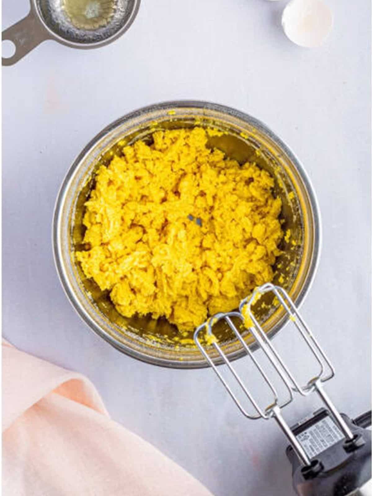Yellow cake mix, melted butter, and an egg mixed into a crust dough in a bowl.