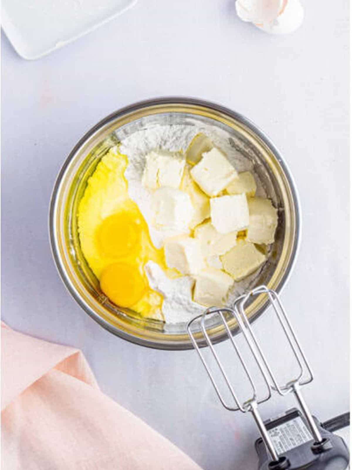Cream cheese, eggs, and powdered sugar added to a bowl for the gooey filling.