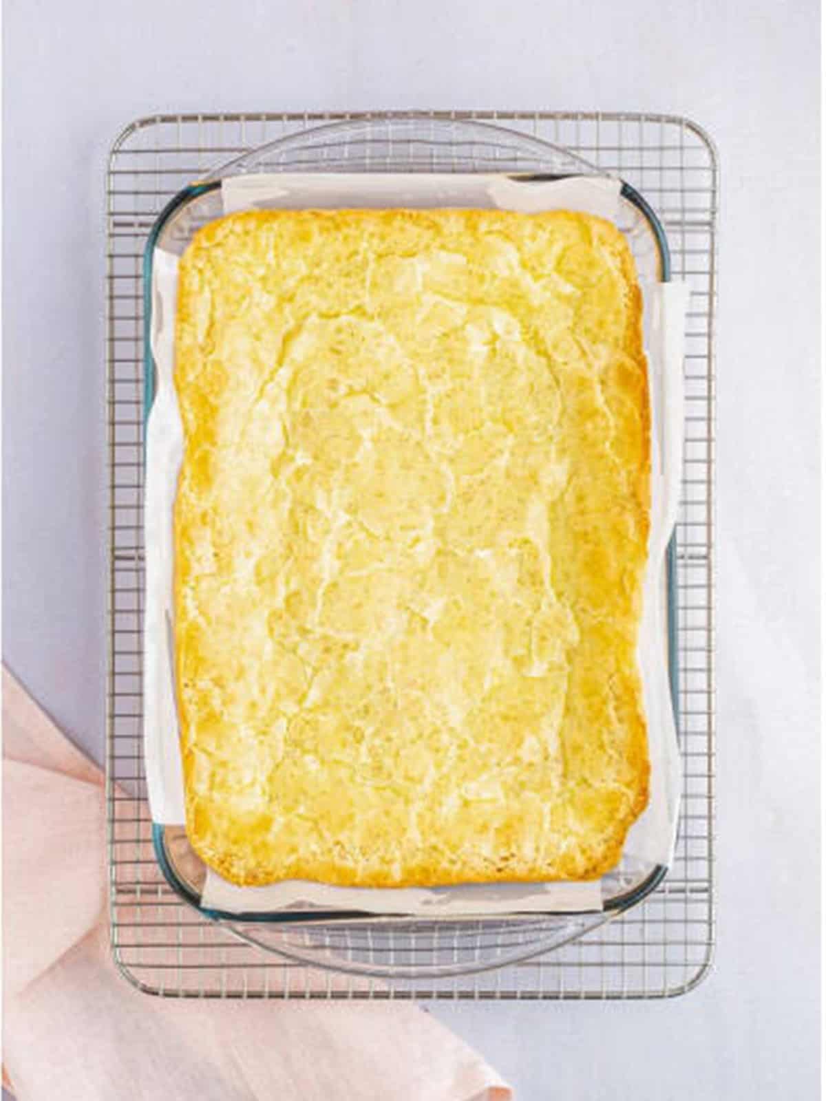 Baked golden gooey butter cake with a crinkly top cooling in the pan.