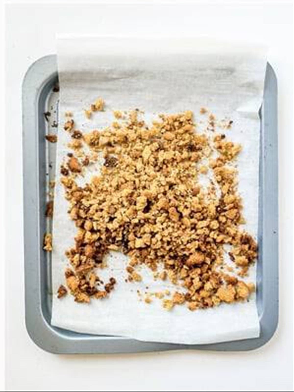 Toasted blondie crumbles on a parchment-lined baking sheet.