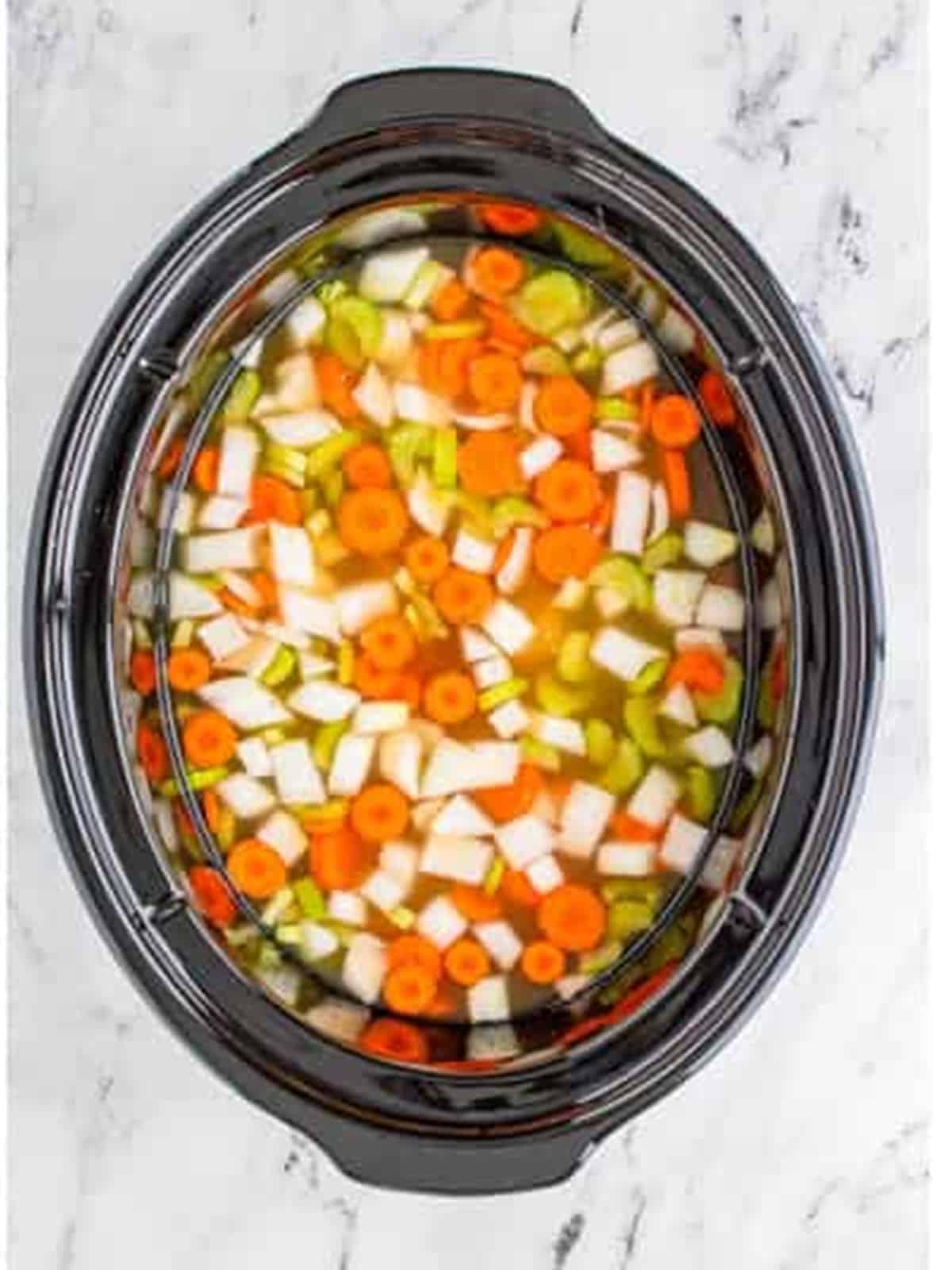 Cooked chicken and vegetables in broth in the slow cooker.