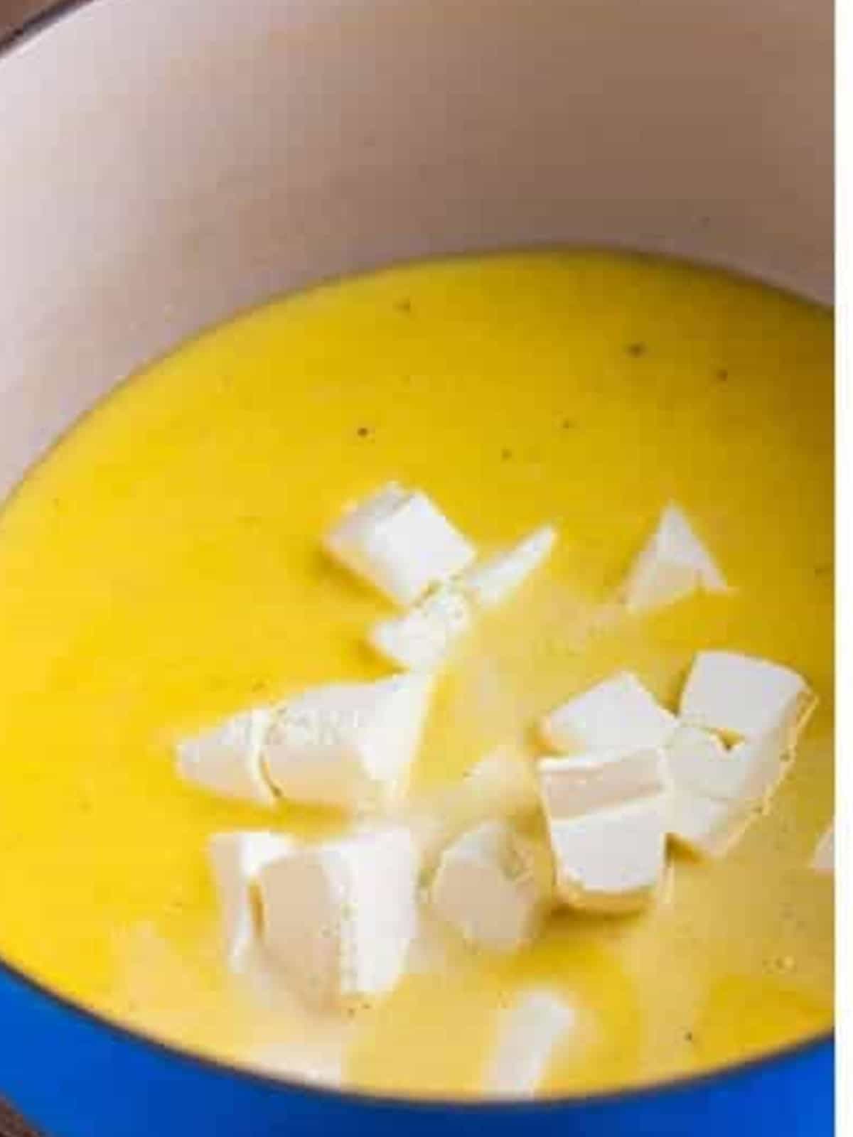 Stirring cubed cream cheese into the alfredo sauce until melted.