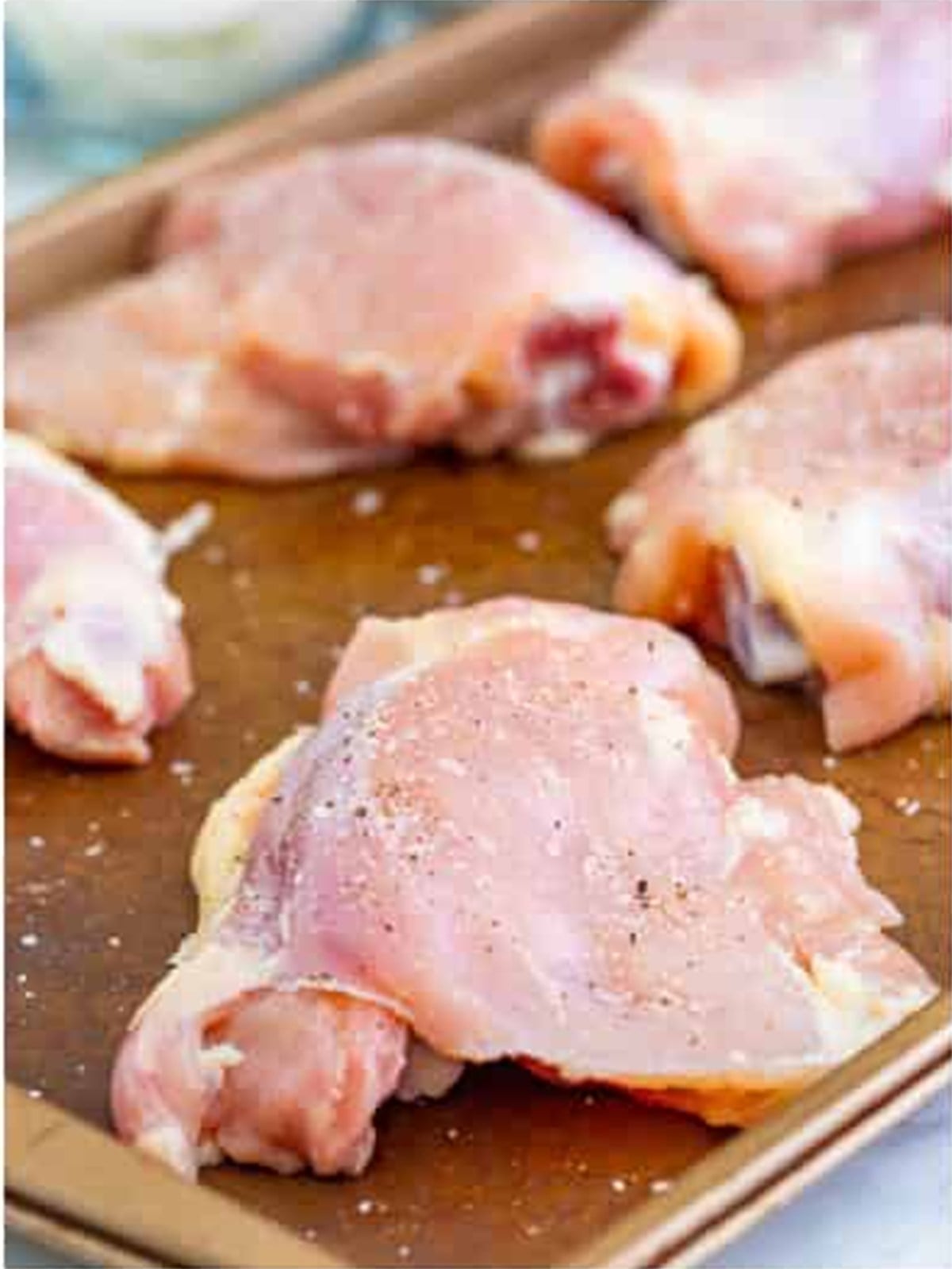 Bone in chicken thighs seasoned with salt and pepper on a sheet pan for chicken cacciatore.